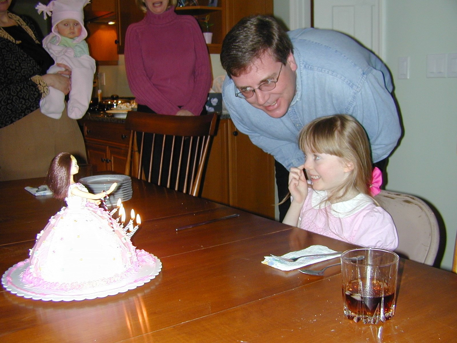 Alan leaning over a young girl beside a birthday cake