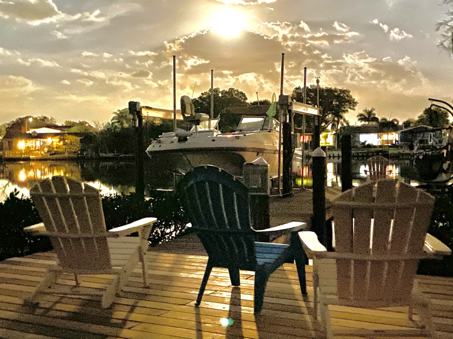 Adirondack chairs on the dock facing a brilliant evening sky.