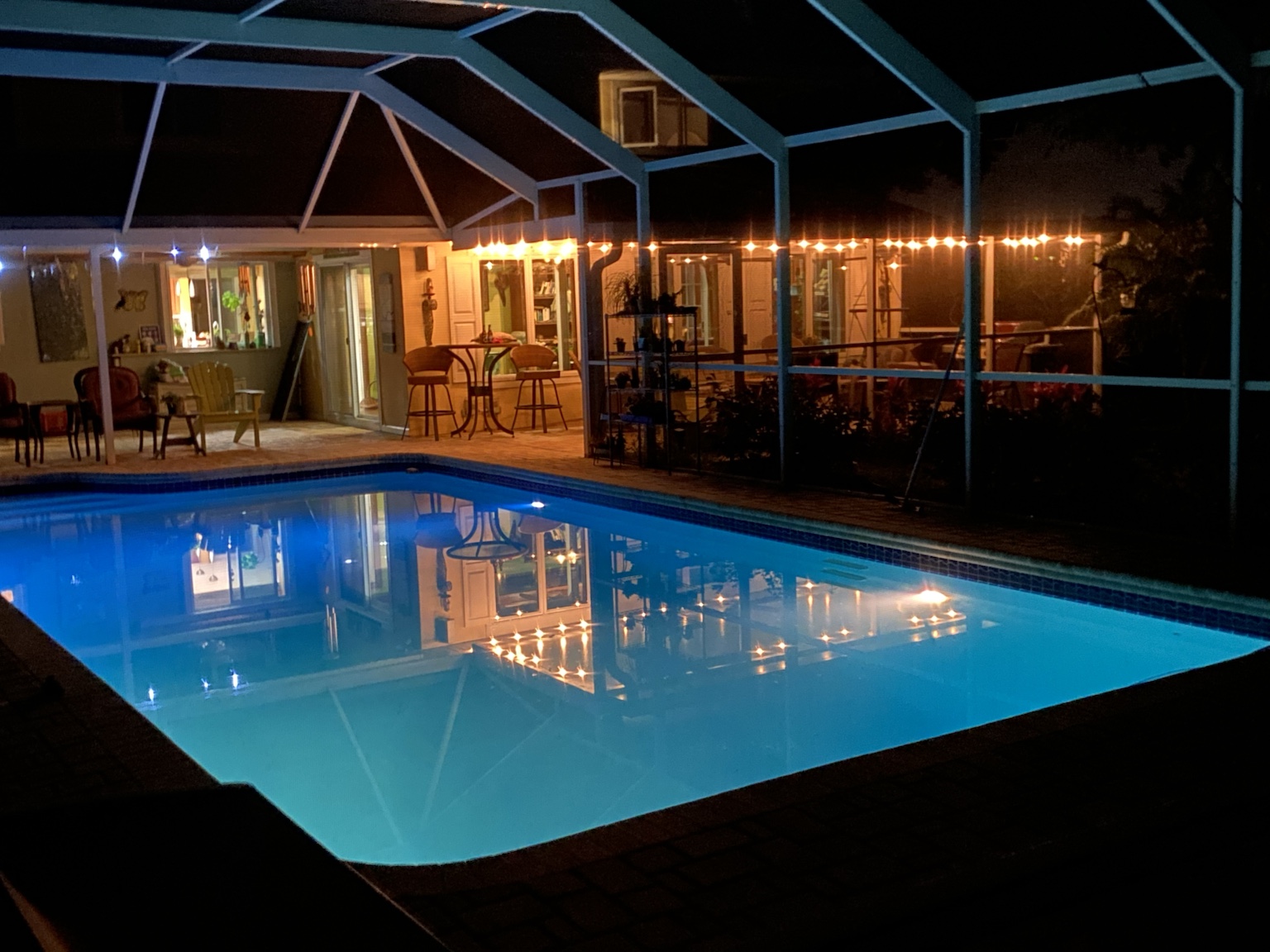 The screened swimming pool glowing blue after dark.
