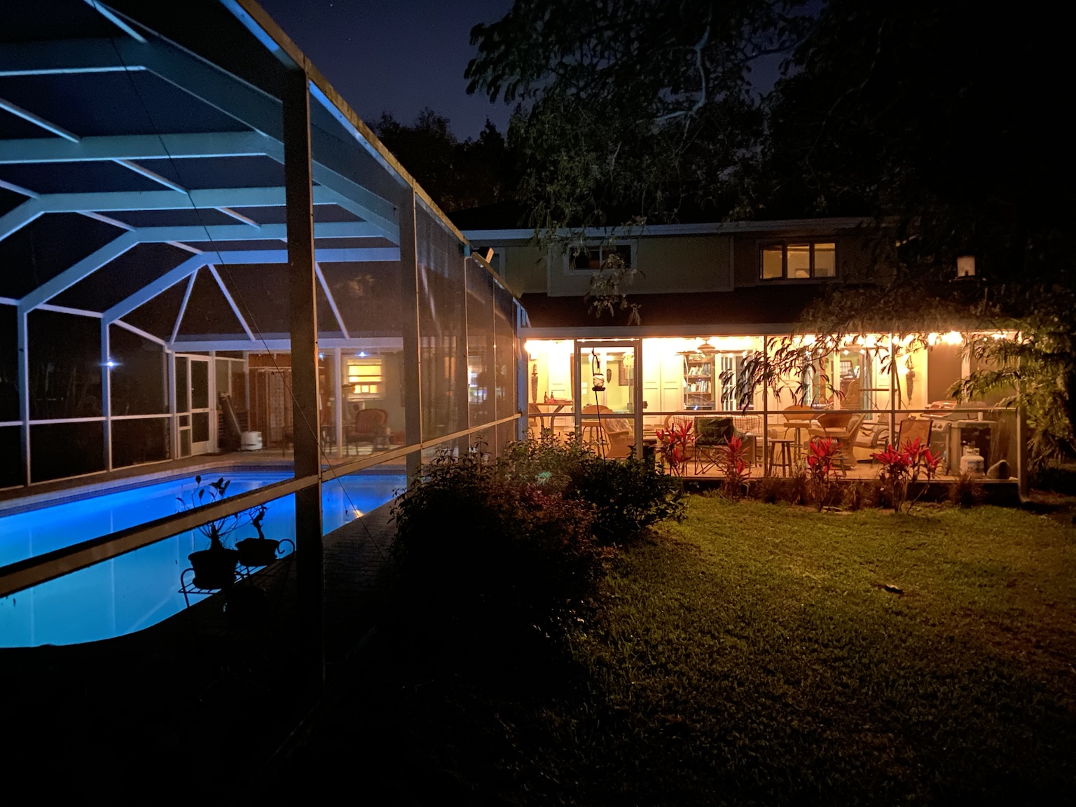 The pool enclosure and house lit warmly on a quiet night.