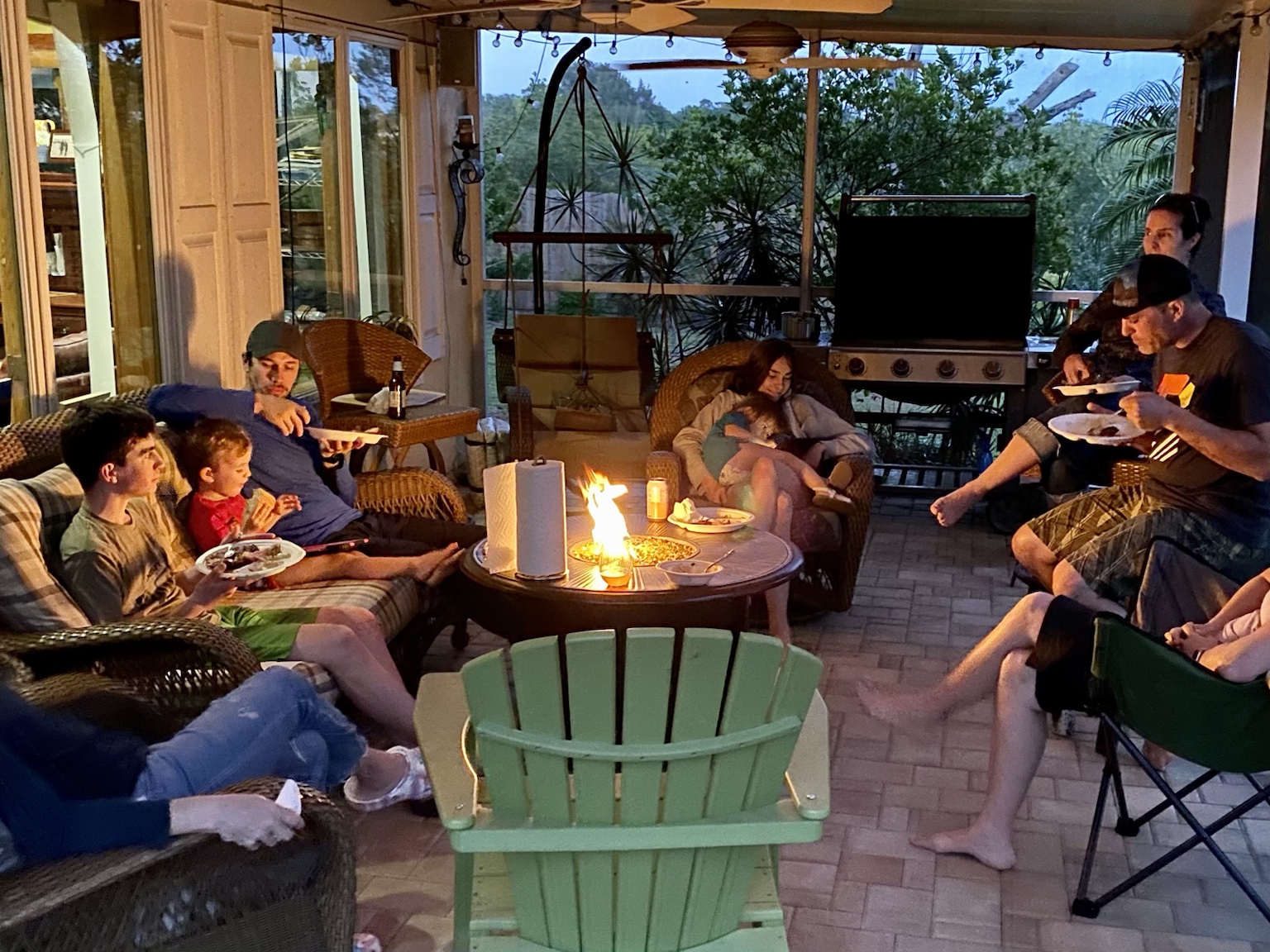 A larger family gathering around the fire on the porch.