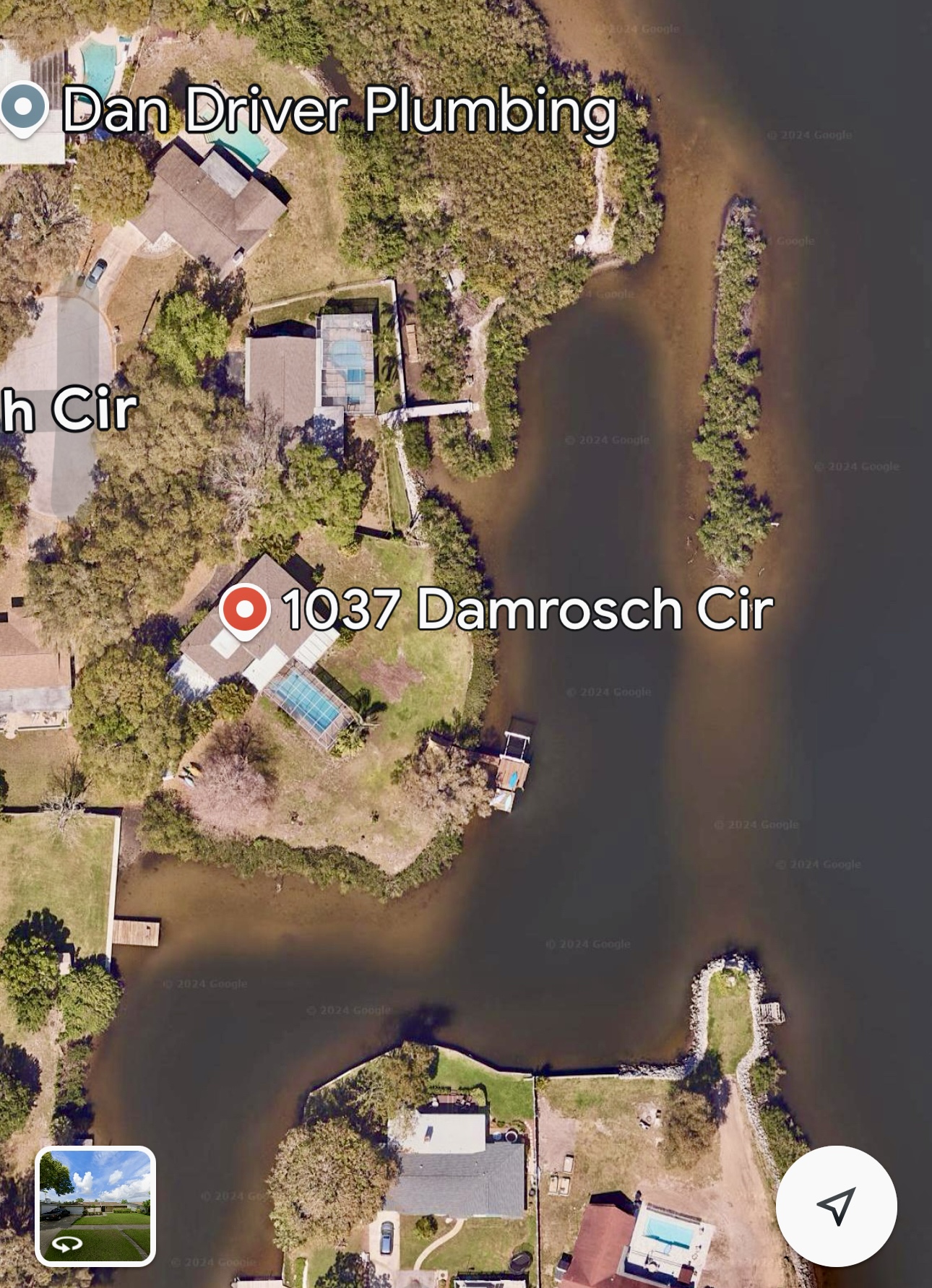 An aerial view showing the house, screened pool, waterfront, long dock, and the narrow island just offshore.