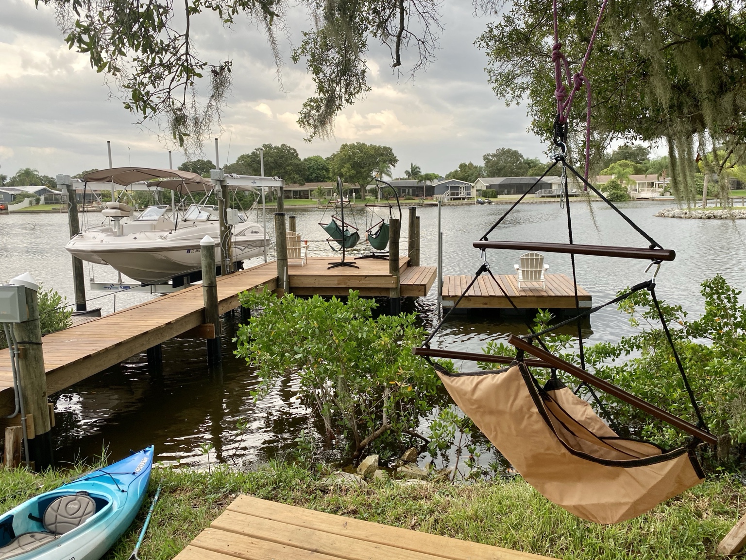 The finished waterfront with our Hurricane boat, forty-foot dock, and hanging chairs beneath the oaks.