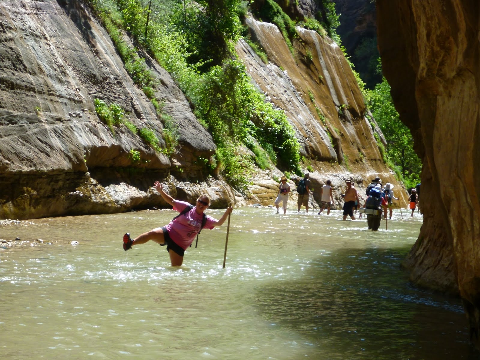 Cindy leaning back into the cool river while holding her walking stick.