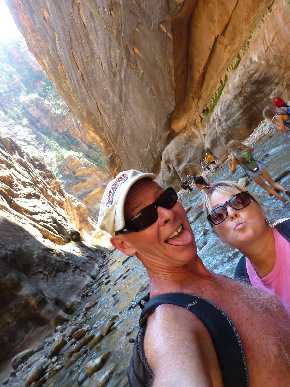 Tim and Cindy beneath steep walls of layered sandstone.