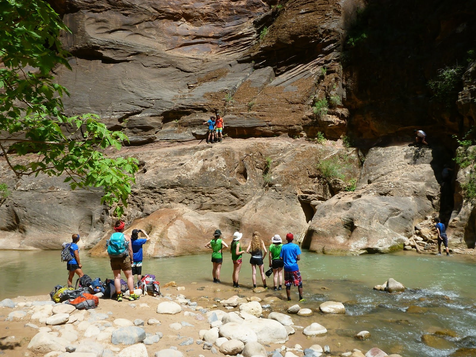 A group of hikers gathering beside a rocky ledge above the river.