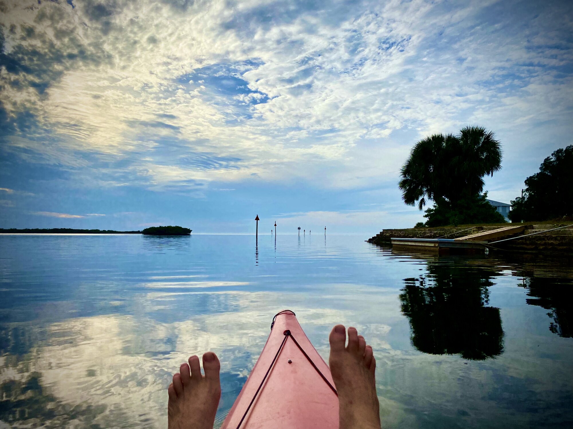 Red kayak entering mirror-calm Gulf channel