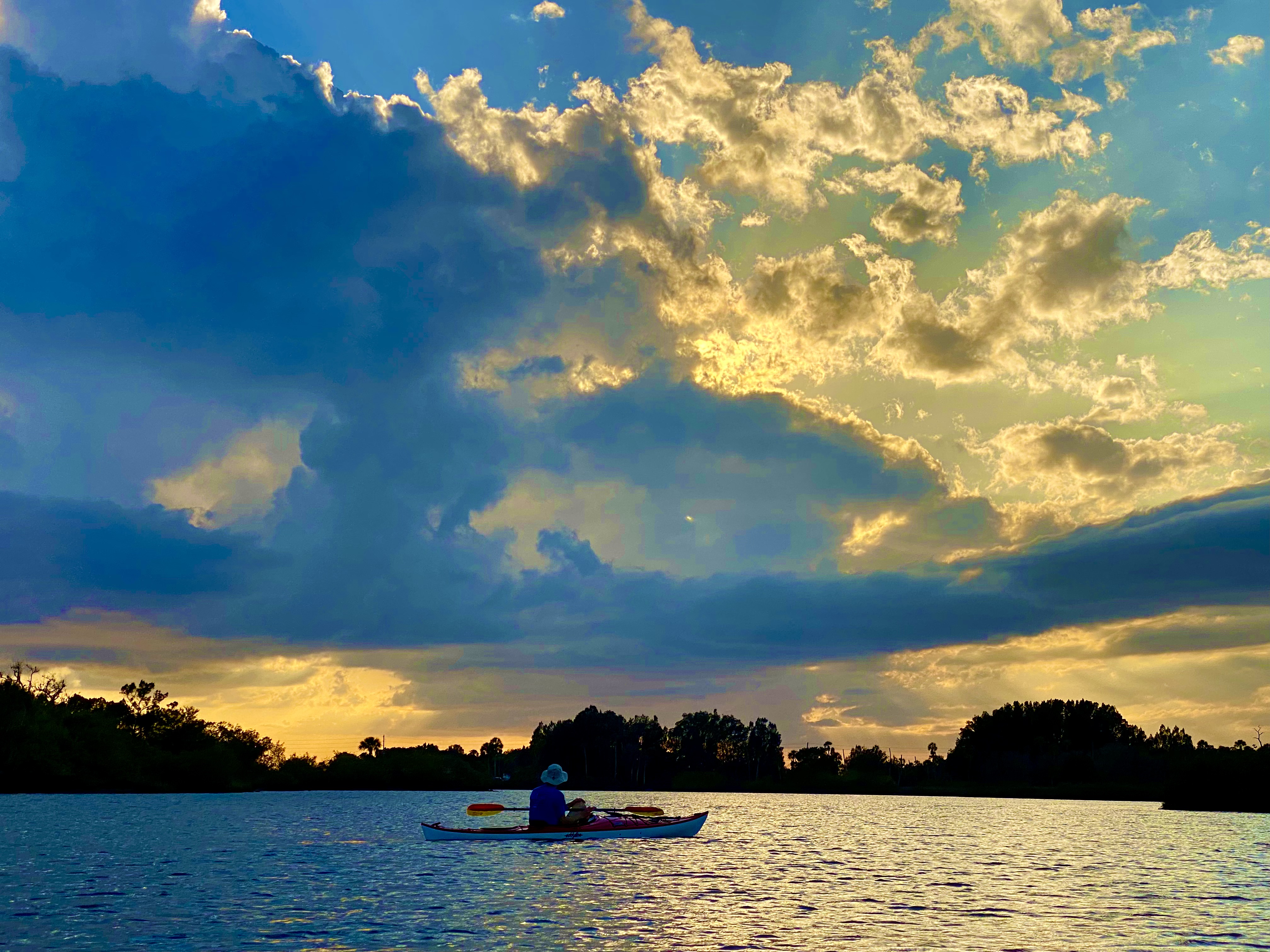 A kayaker beneath dramatic evening clouds near Aripeka