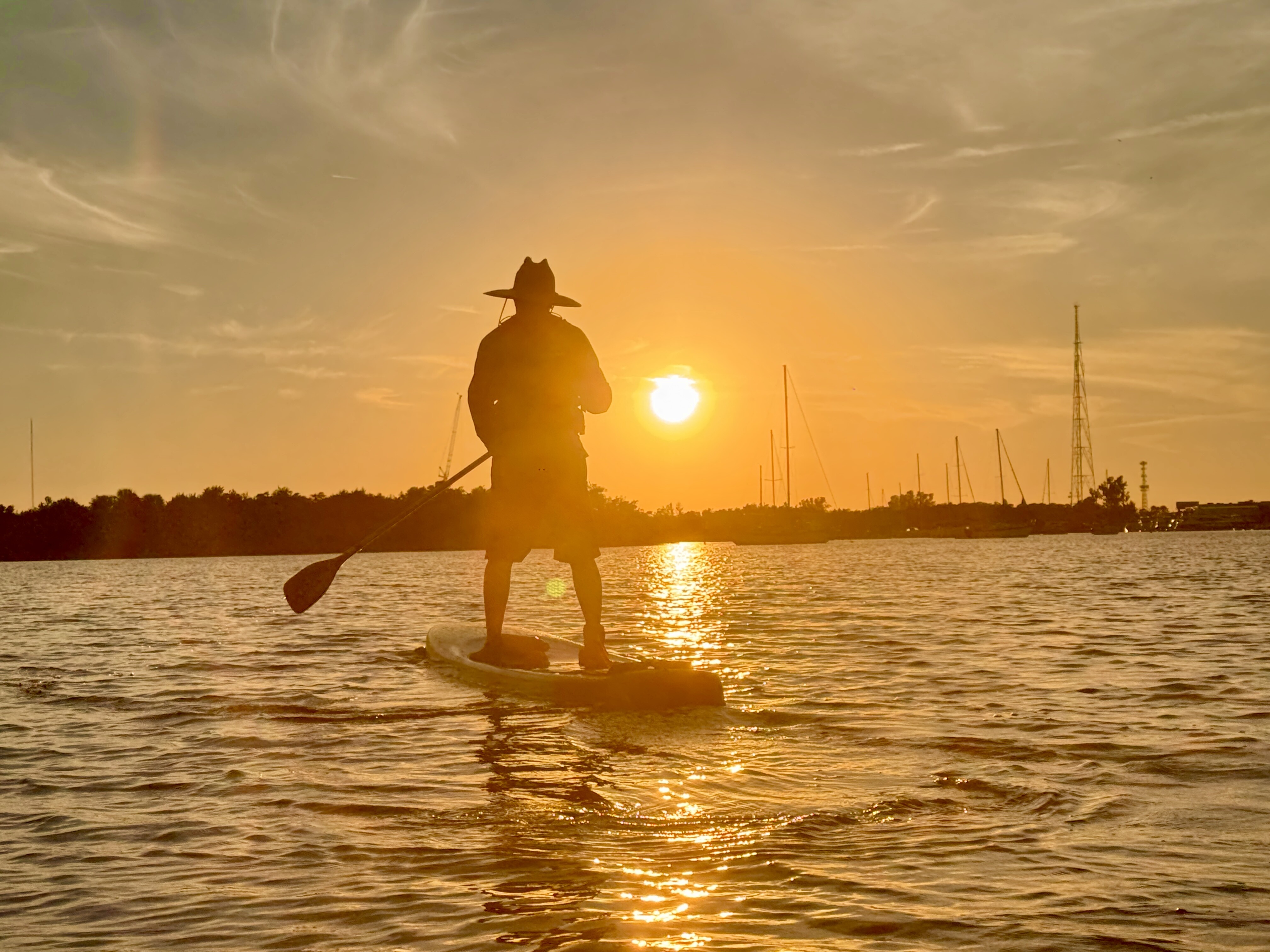 Robbie paddling across golden water at sunset