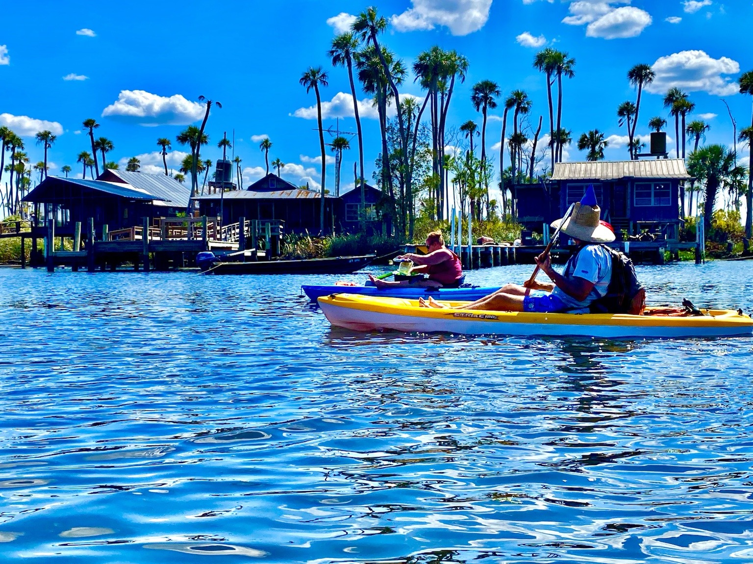 Kayaks passing the distinctive fish-camp and riverside architecture along the Chaz.