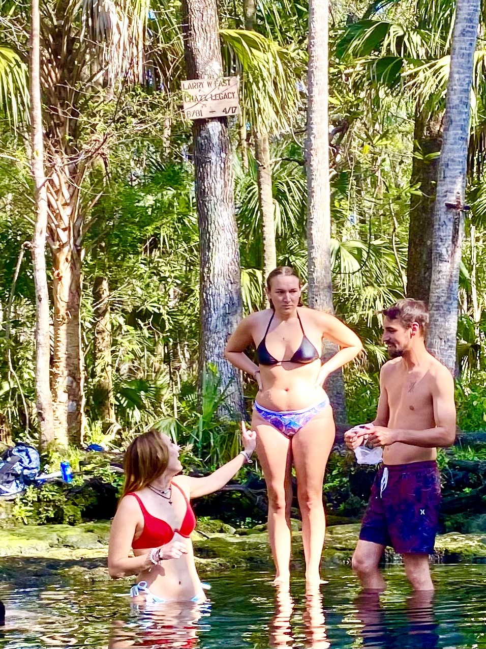 Friends visiting beside the spring while kayaks wait nearby.