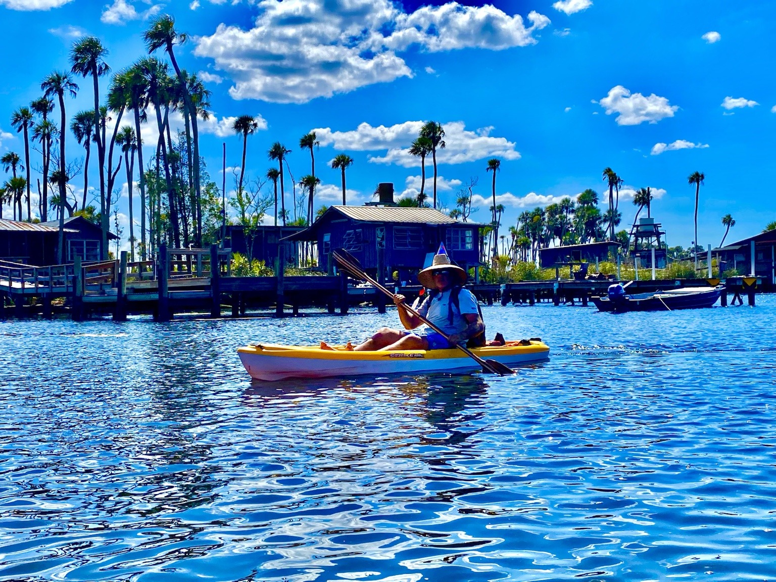 A paddler passing a riverside fish-camp style building along the main river.