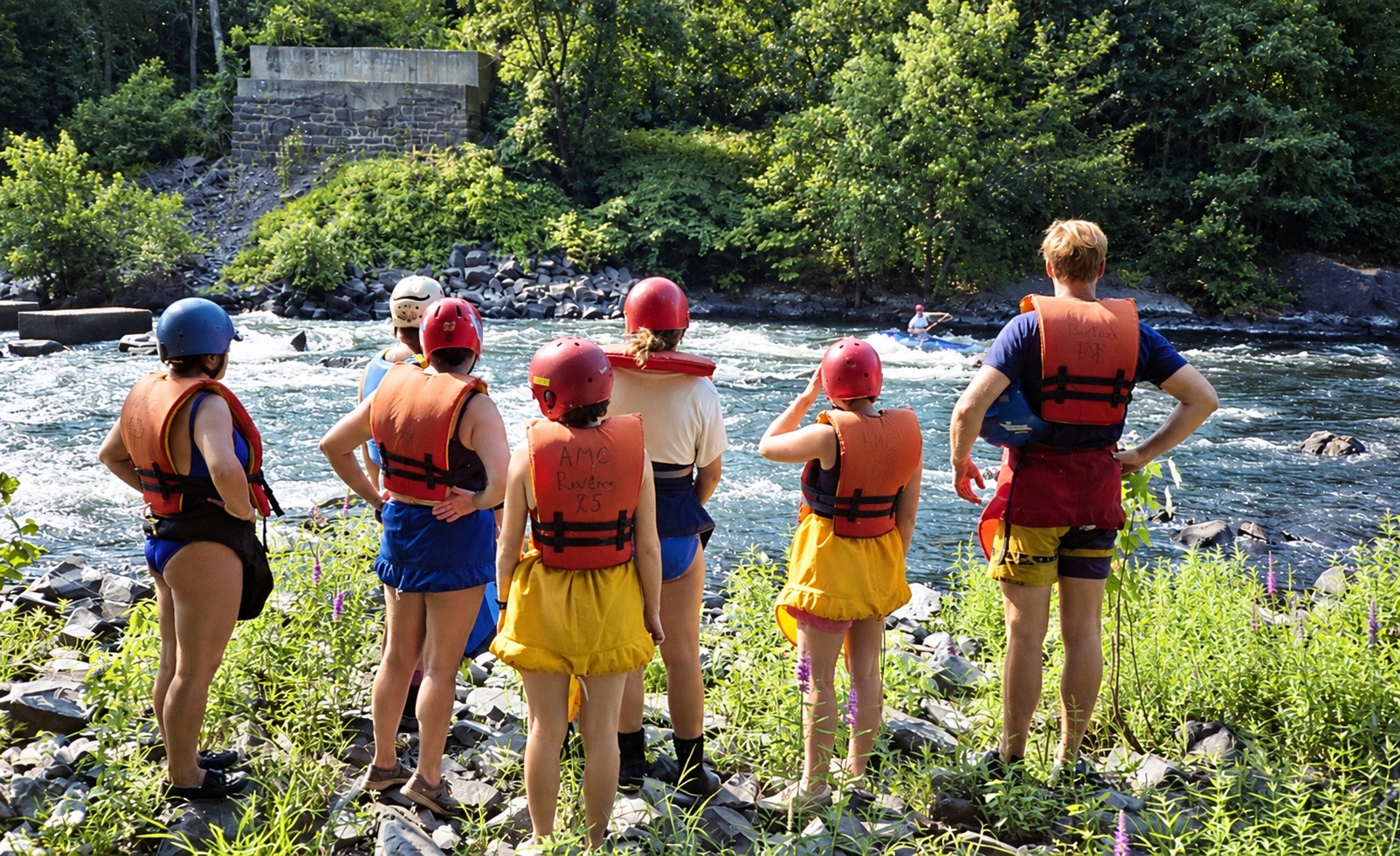 Watching a paddler on the river, with helmets and PFDs ready.