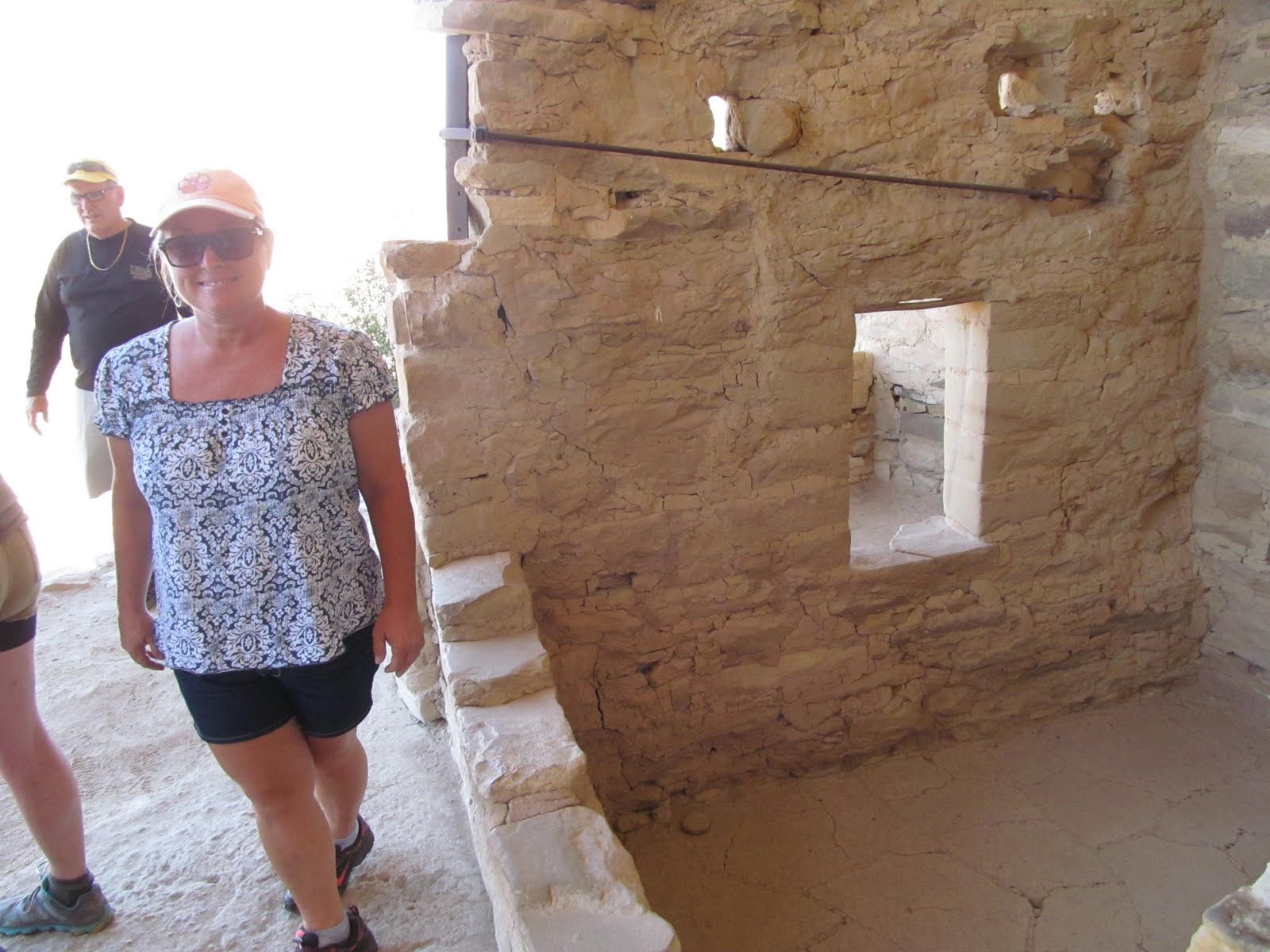 Cindy beside carefully fitted masonry walls inside the cliff dwelling.