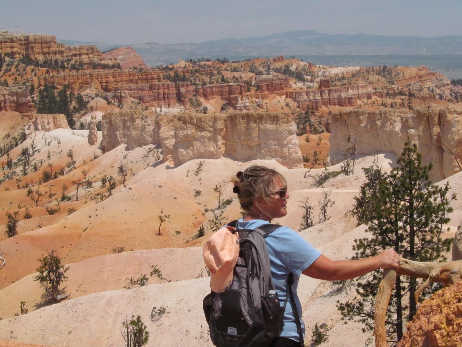 Cindy pausing at a railing with hoodoos spreading out below.