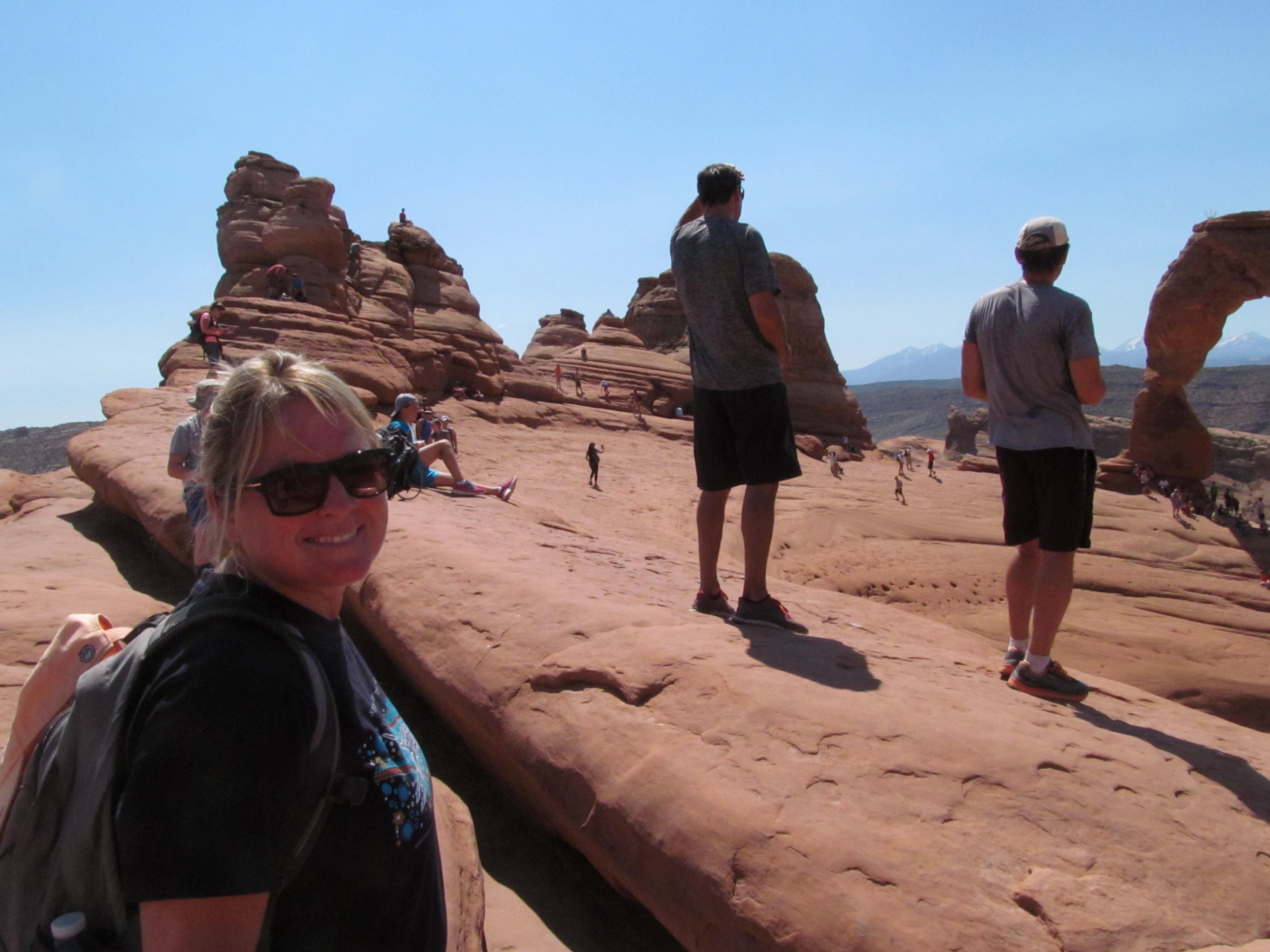 Cindy at the Delicate Arch viewpoint with the La Sal Mountains beyond.