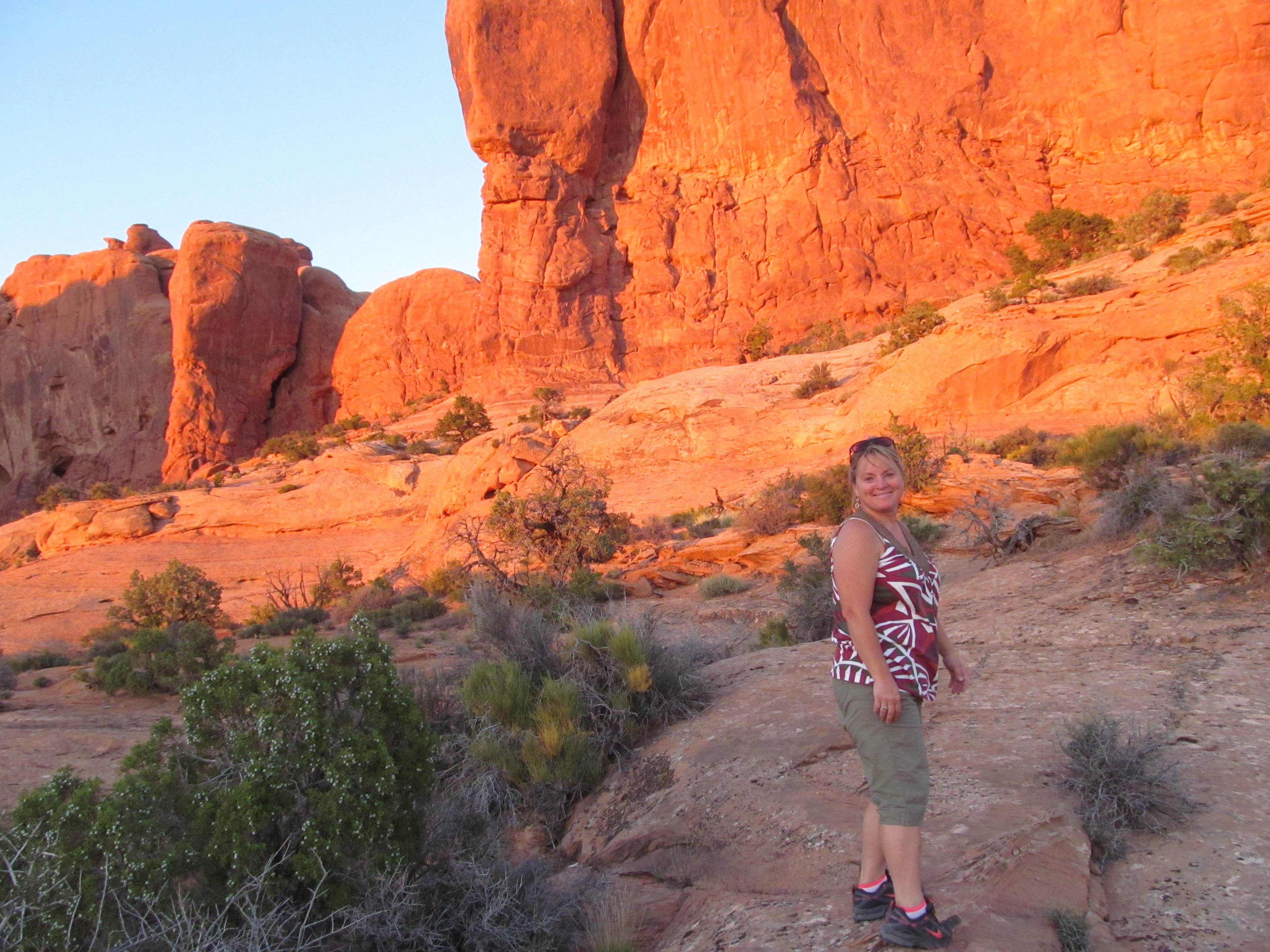 Cindy walking through glowing red rock near the end of the day.