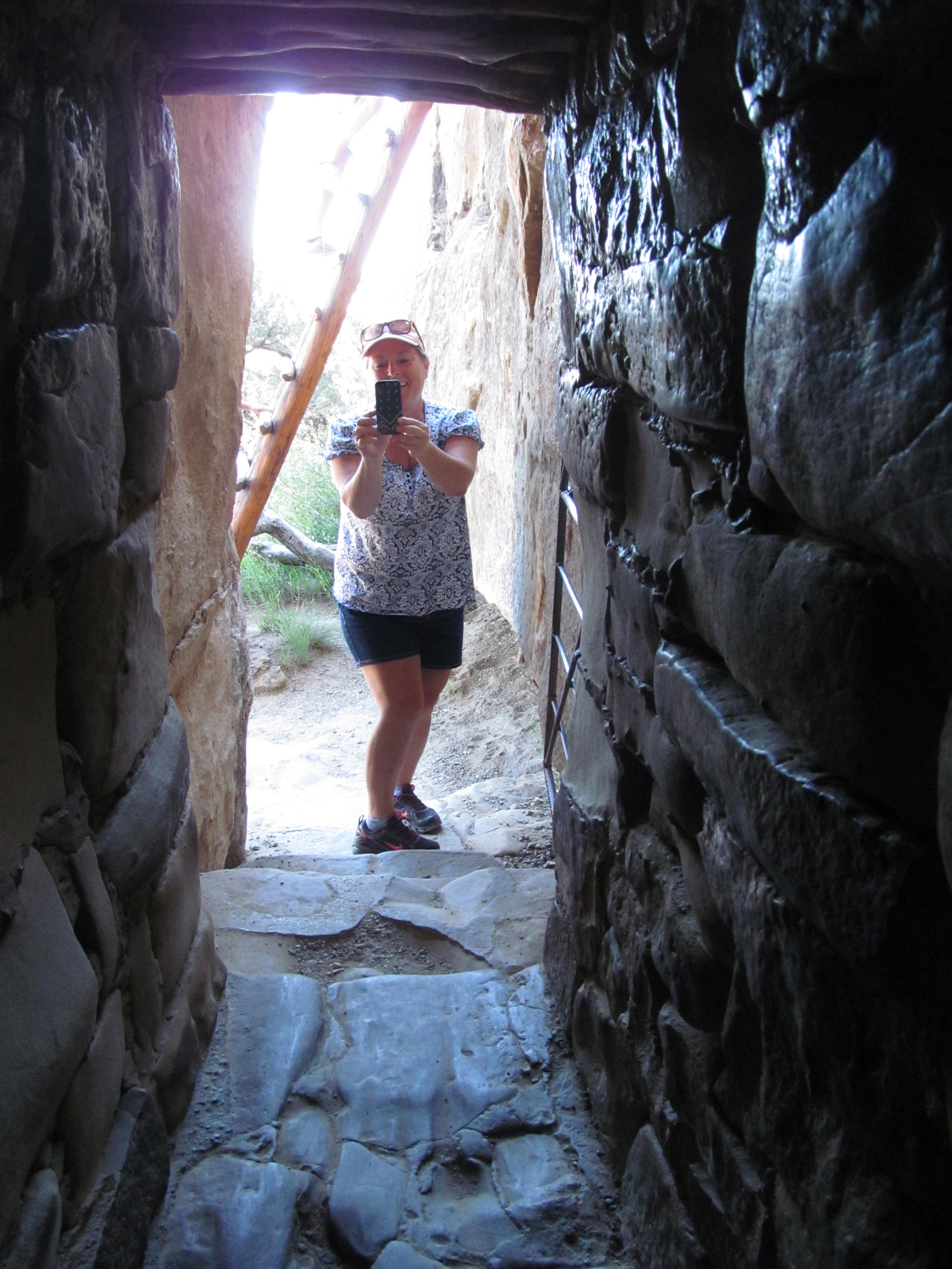 Cindy framed by a narrow stone passage inside the cliff dwelling.