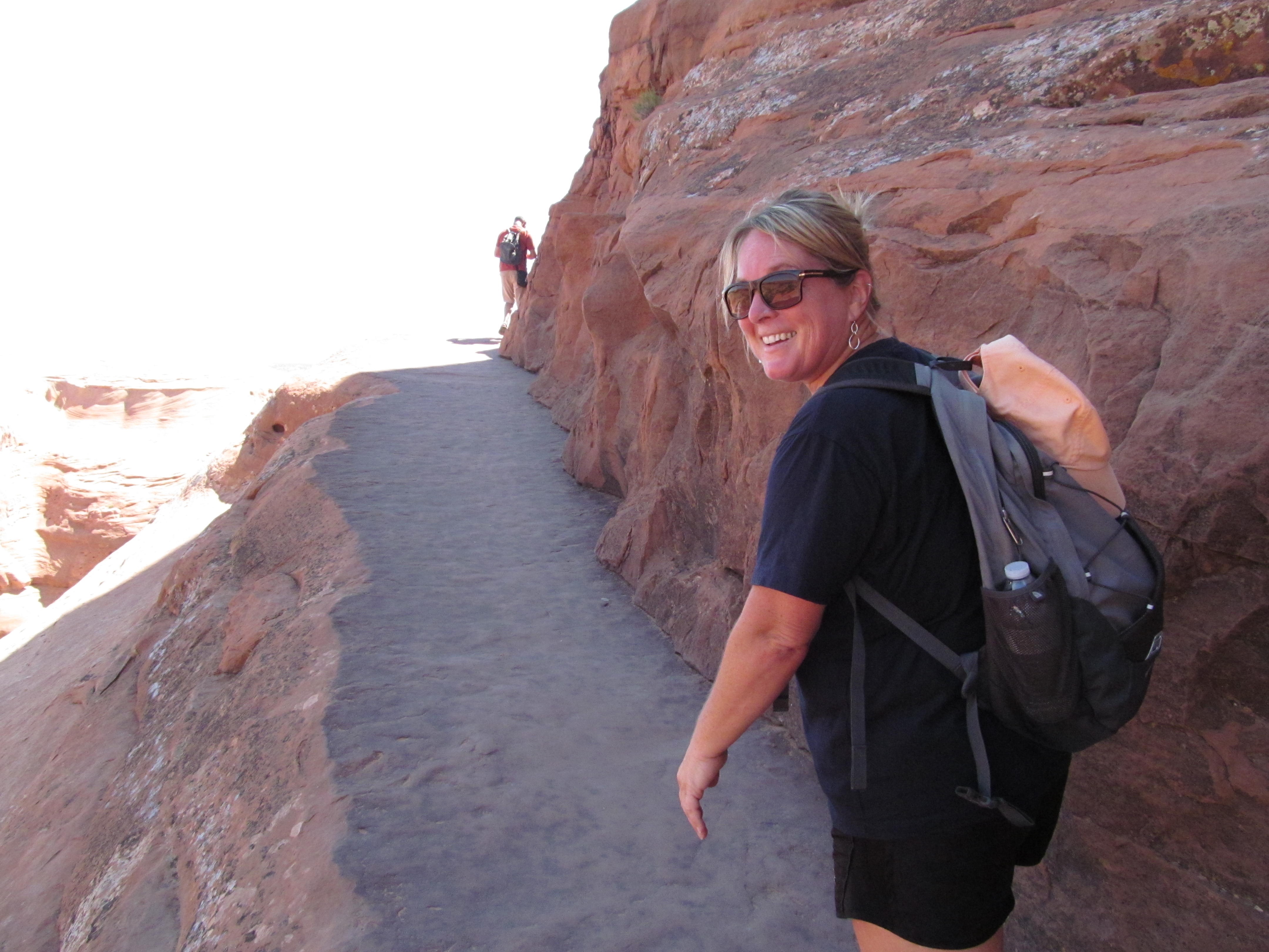 Cindy following a narrow sandstone trail above the desert.