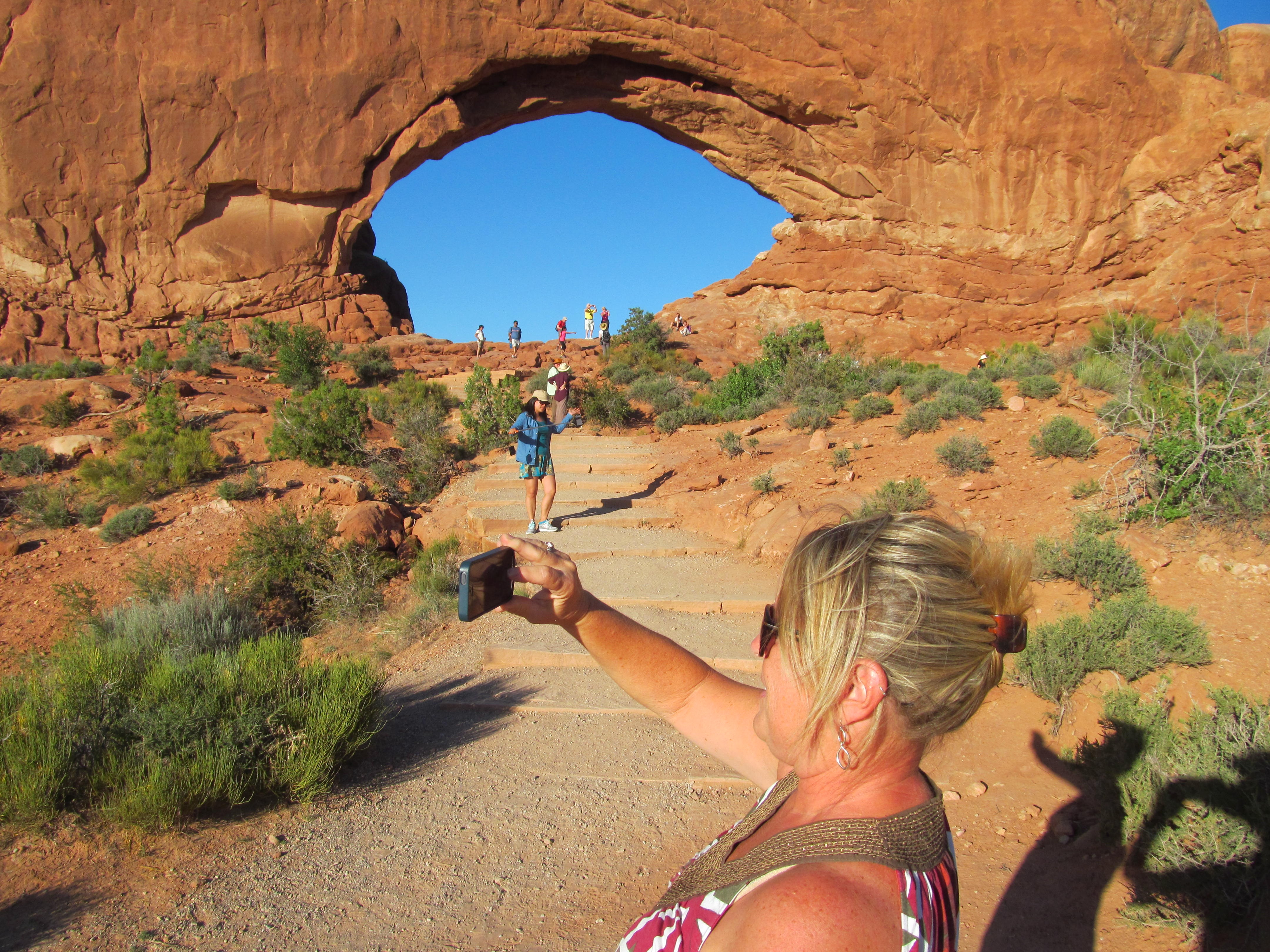 Cindy pointing through a huge natural window in the sandstone.