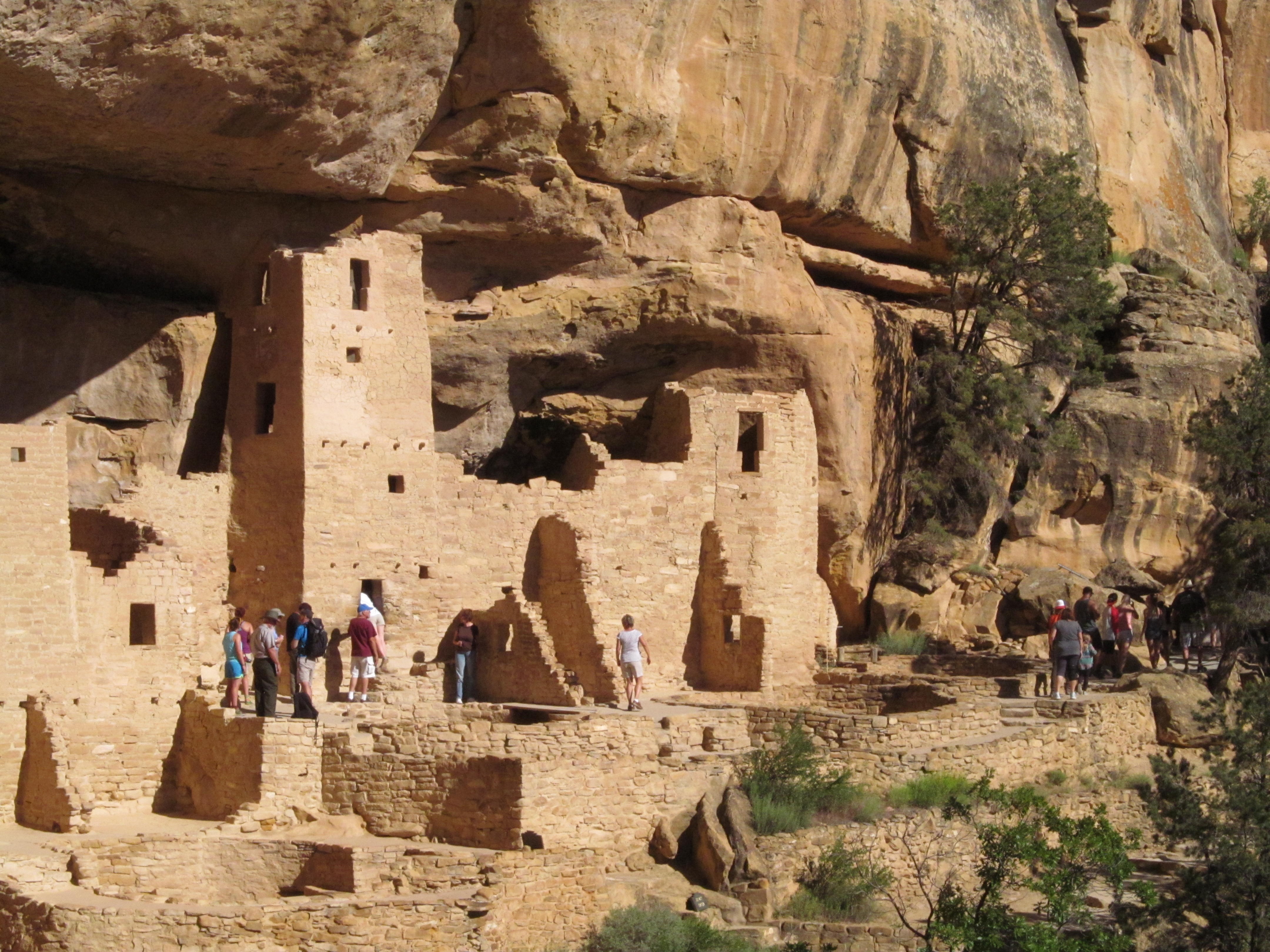 Visitors dwarfed by the architecture and sandstone ceiling of Cliff Palace.
