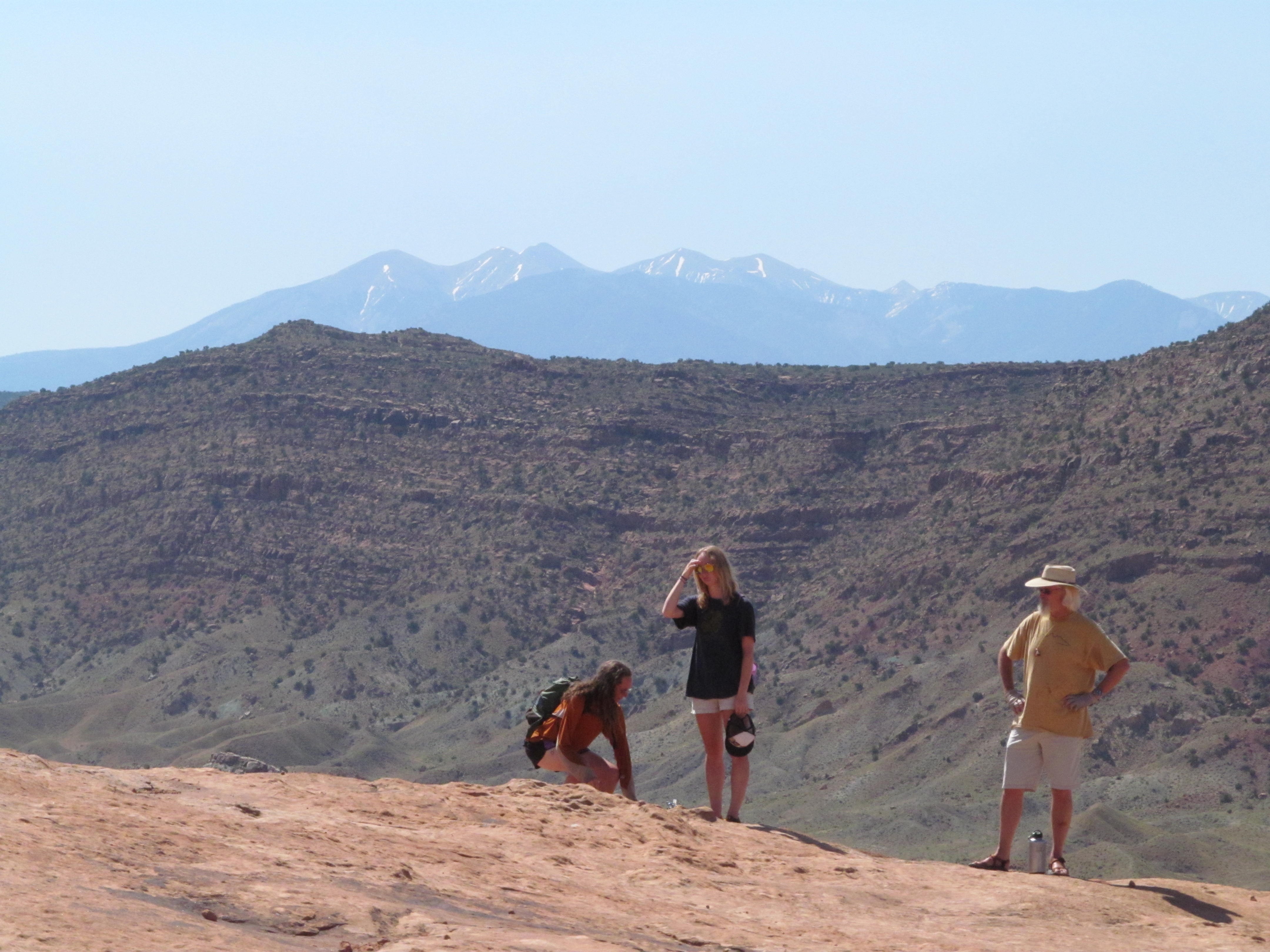 Hikers looking across the wide desert and distant mountains.