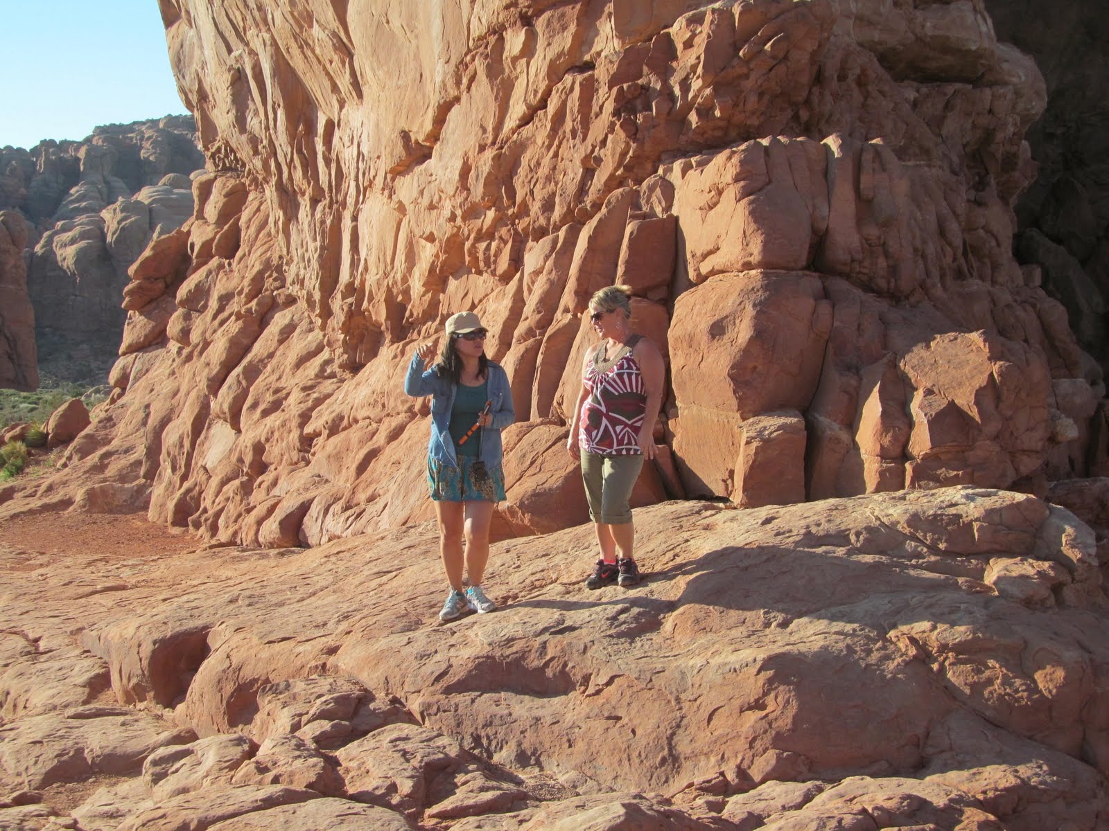 Hikers crossing a broad sandstone shelf in Arches National Park.