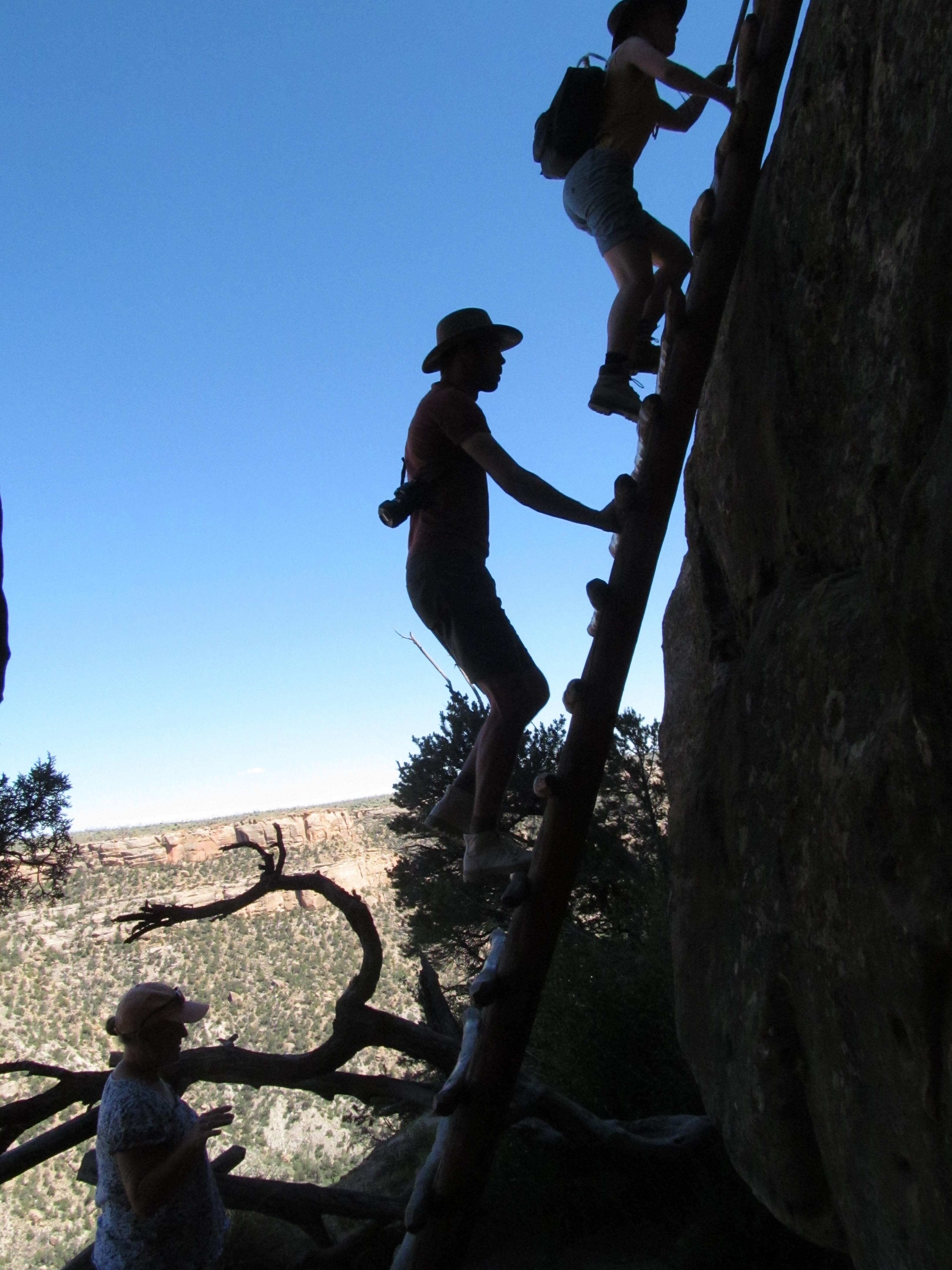 A visitor silhouetted while climbing from the cliff dwelling toward the mesa top.