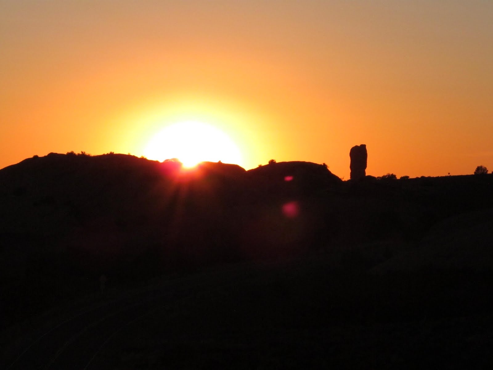 The sun dropping behind the rock formations at Arches National Park.