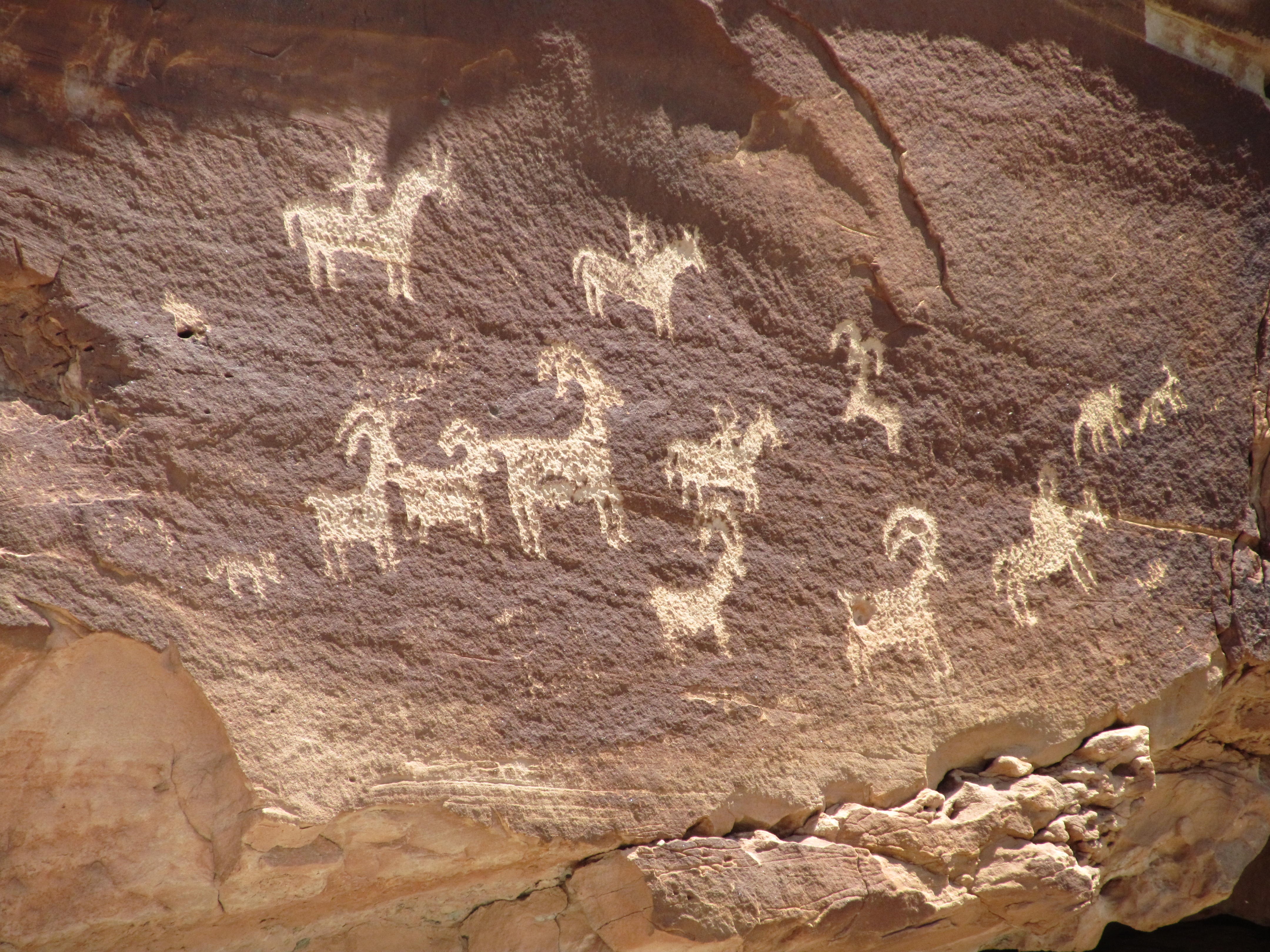 A petroglyph panel preserved on a dark desert rock face.
