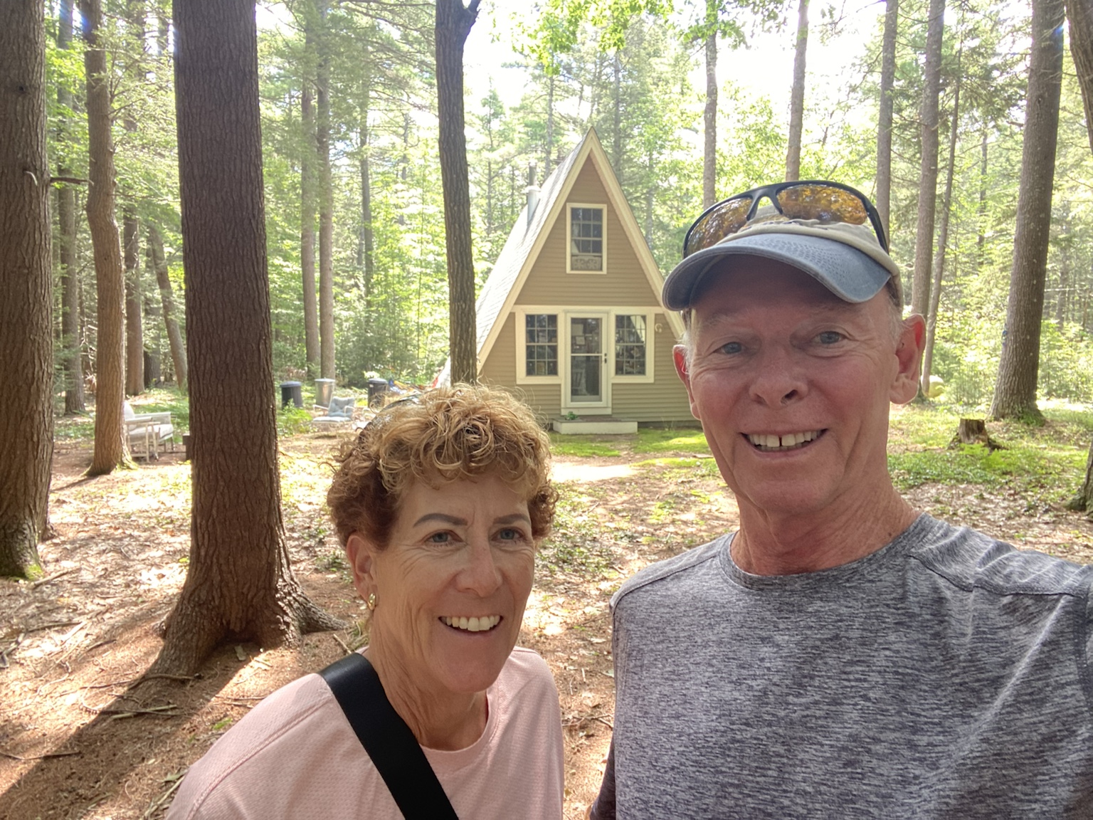 Tim and Kym in the woods beside a small A-frame cabin.