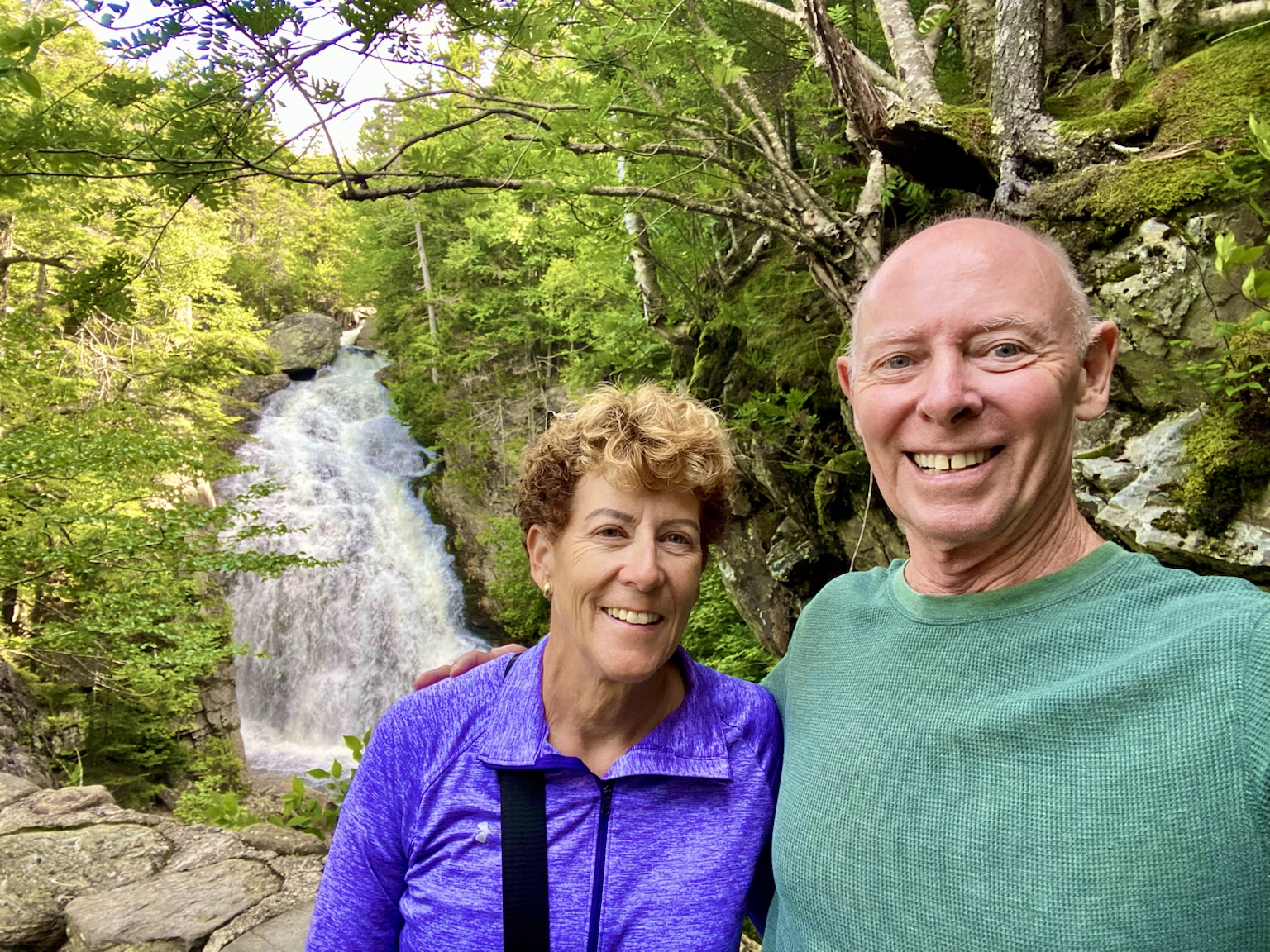 Tim and Kym beside a rushing waterfall in the forest.