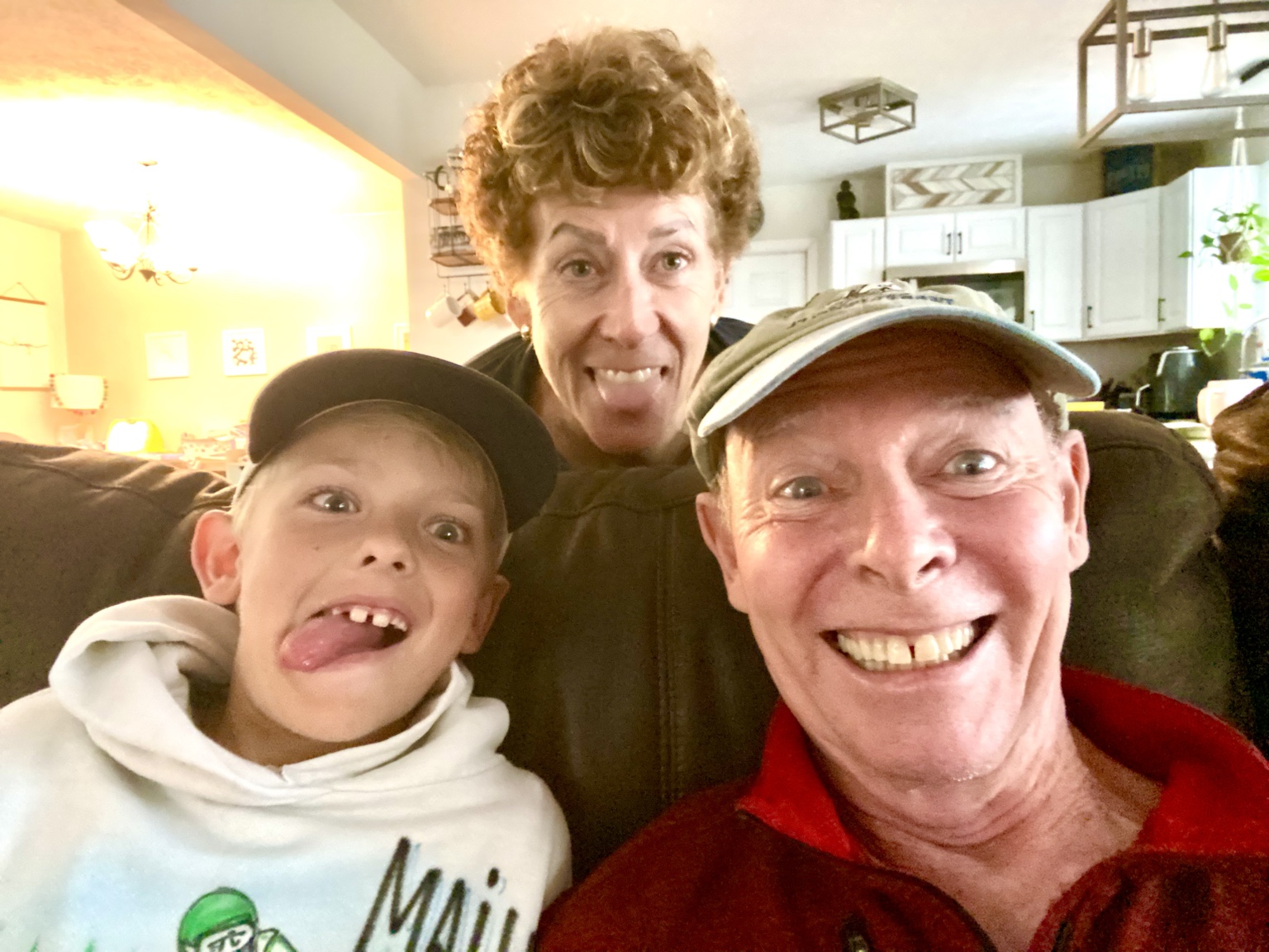 A playful family selfie with Tim, Kym, and a young boy all making faces.