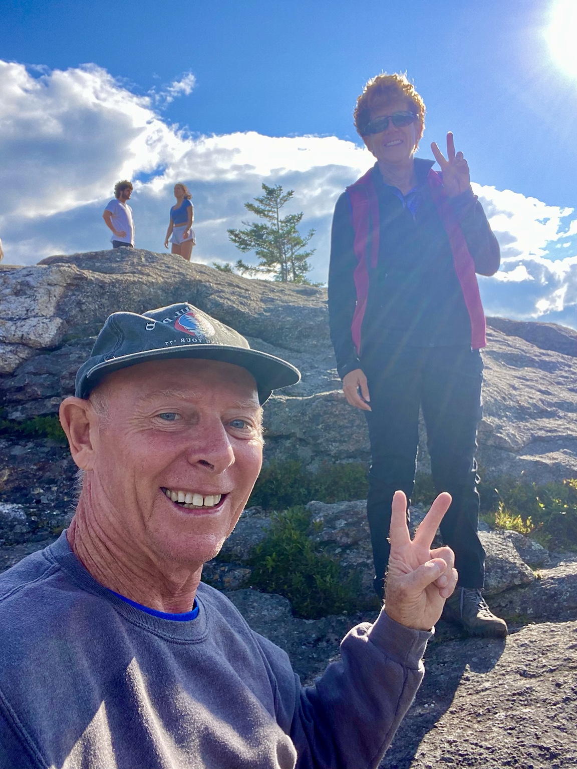 Tim and Kym flash matching peace signs during a sunny mountain hike.