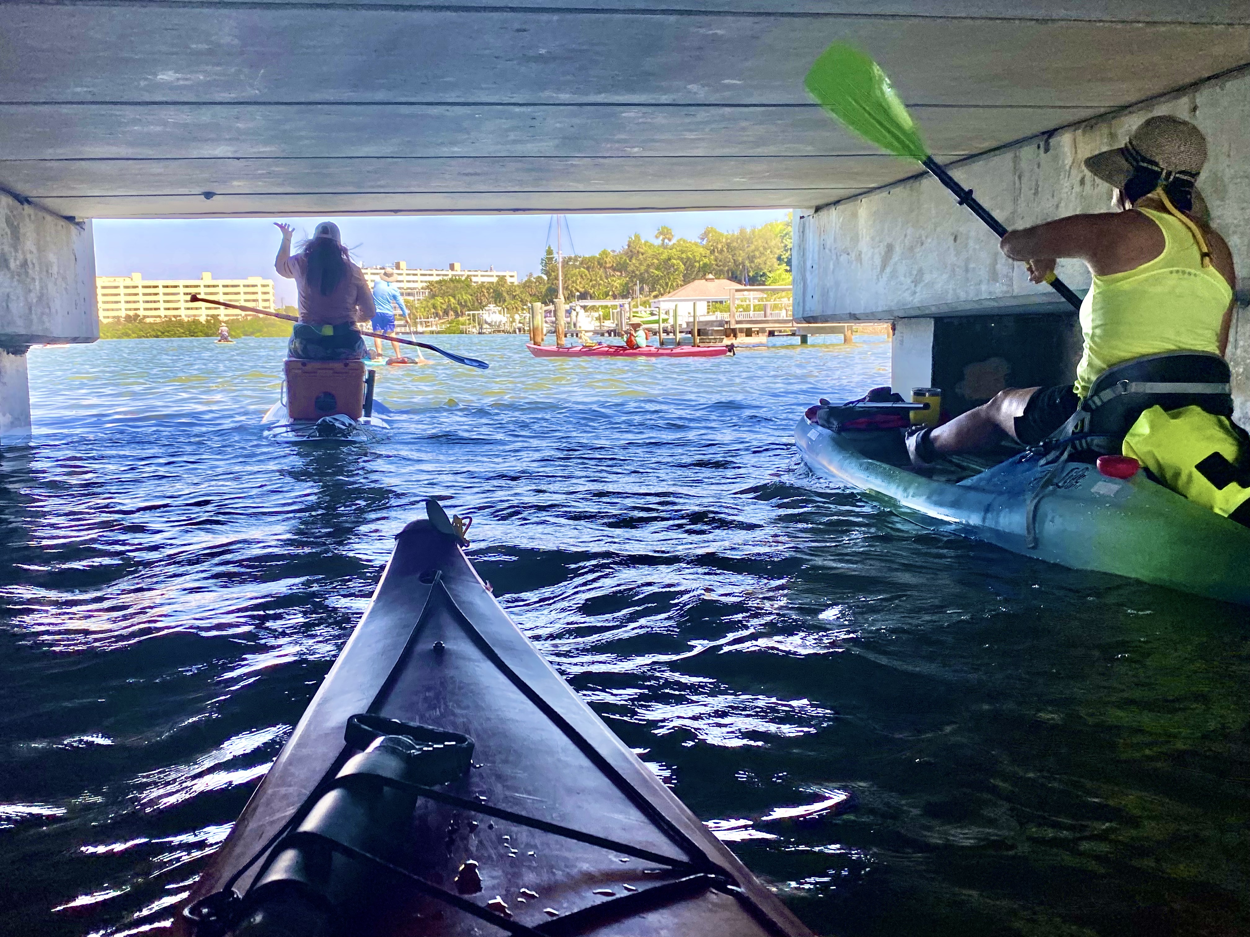 The group passes through the shade beneath the Belleair Causeway bridge.