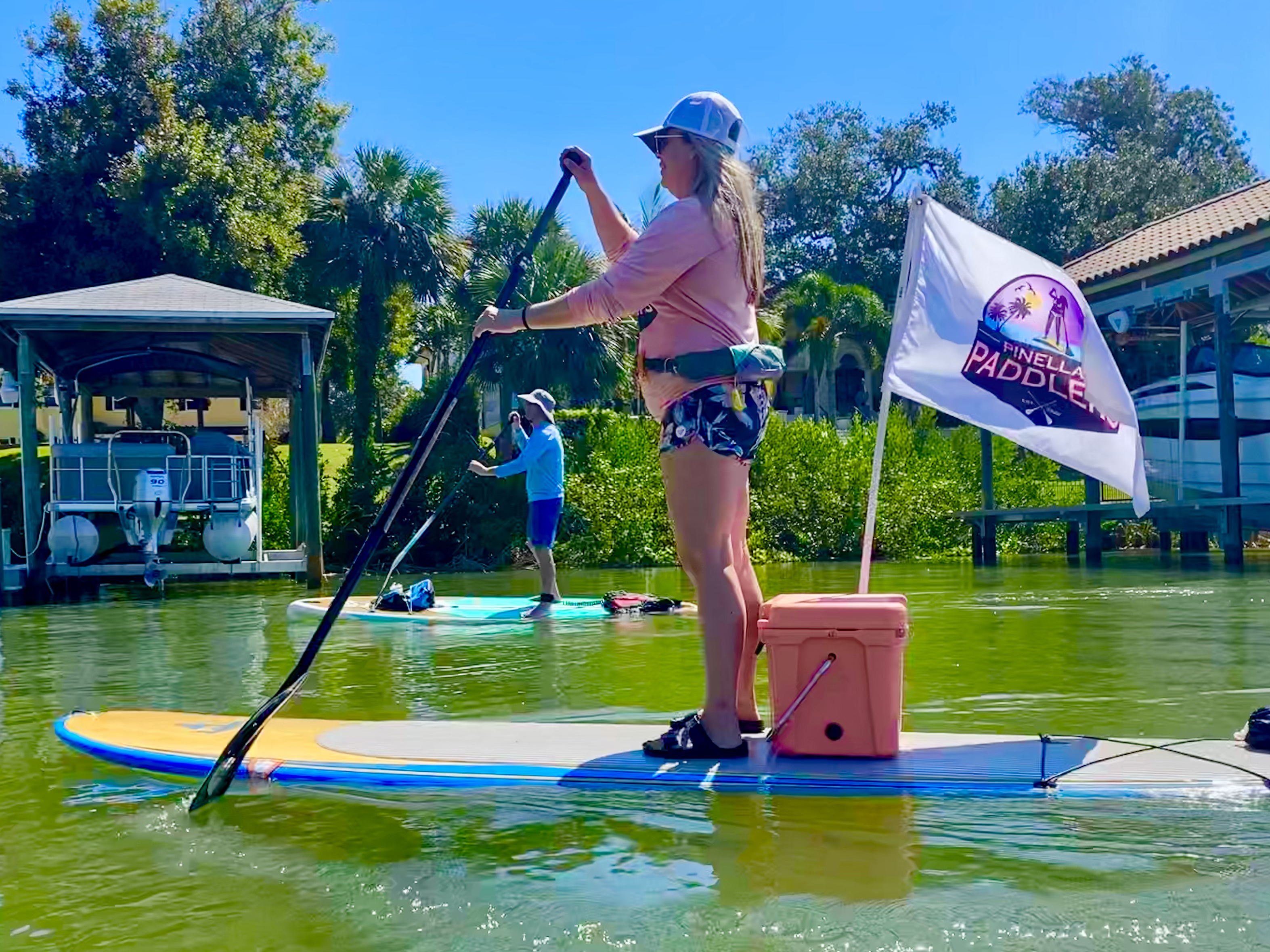 A stand-up paddler eases through the shallow water near the launch area.
