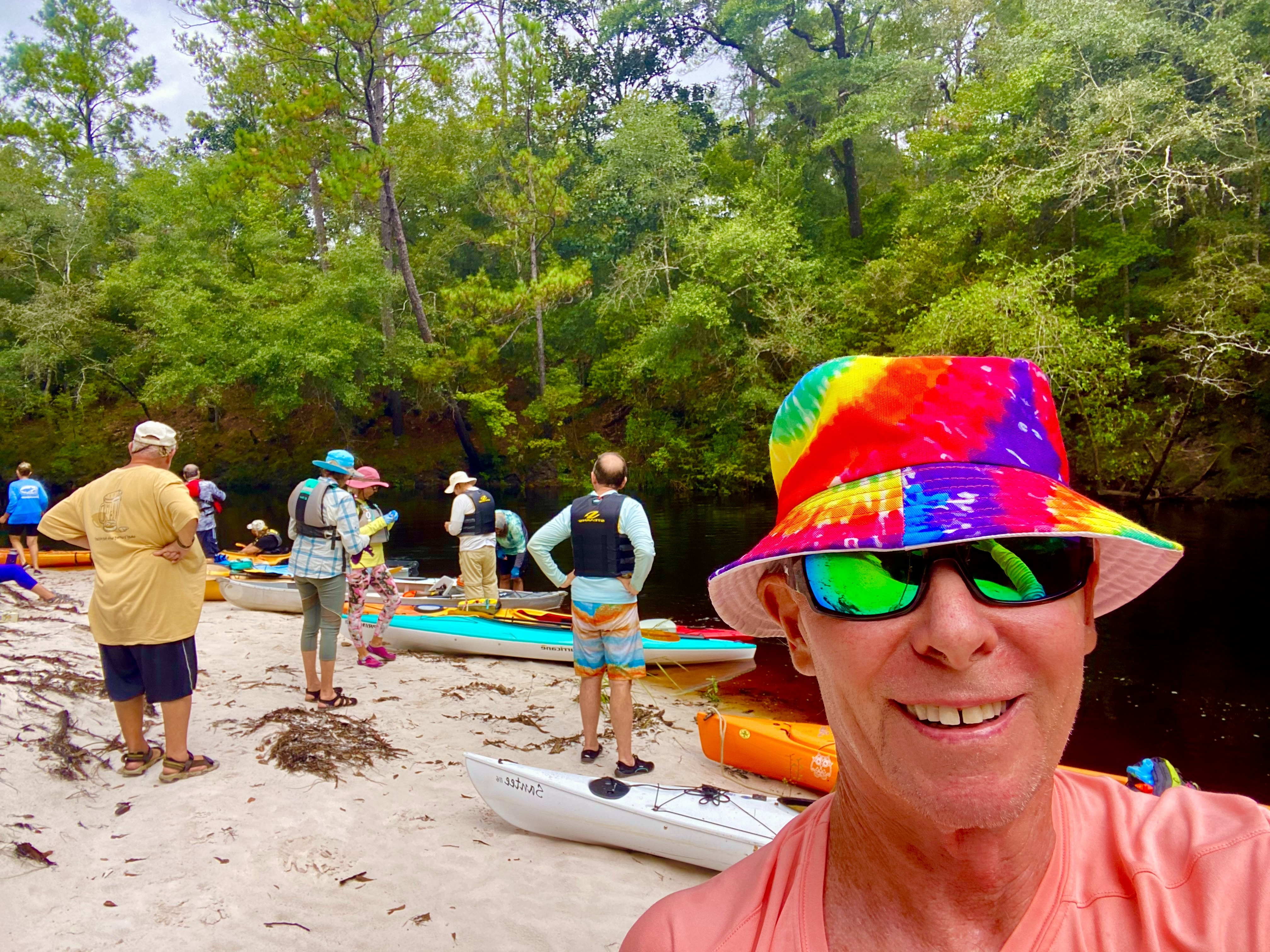 Paddlers and kayaks gathered on a sandbar beside the Sopchoppy River