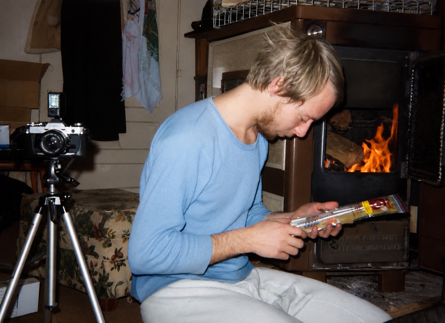 Young photographer beside a tripod and wood stove