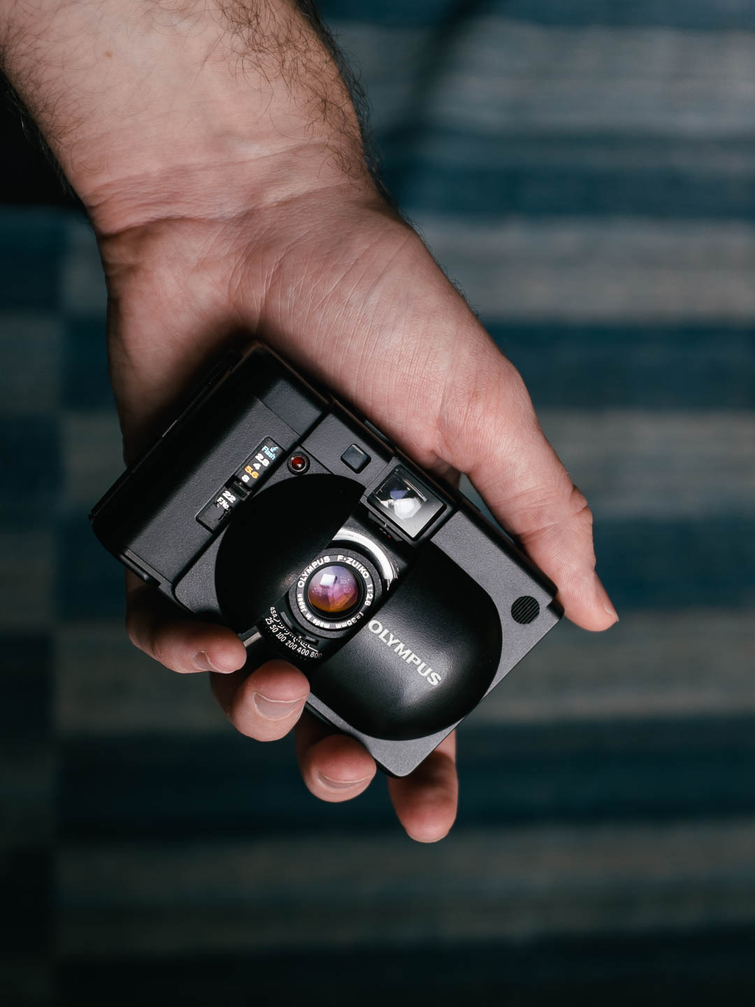 The Olympus XA open, revealing the sharp little lens behind its sliding cover.
