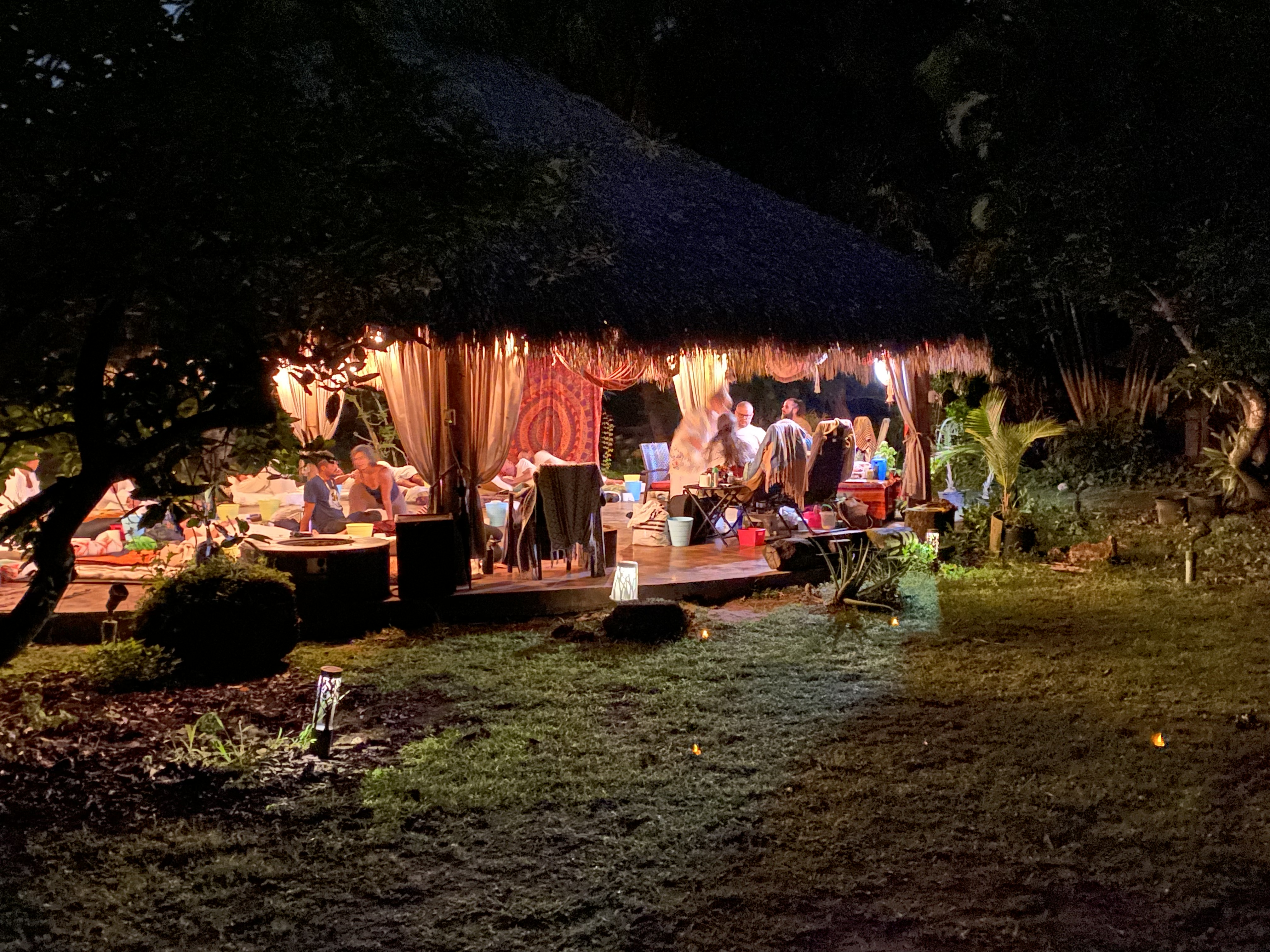 The softly illuminated pavilion viewed from the garden after nightfall.