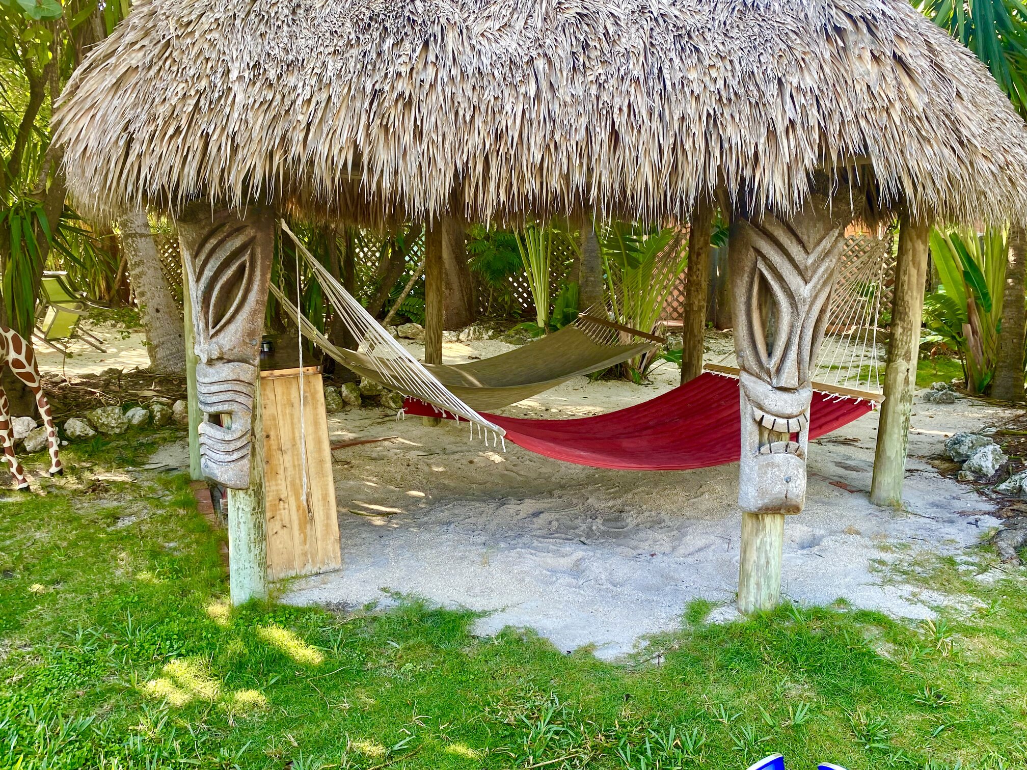 A hammock waiting beneath a palm-thatched shelter.