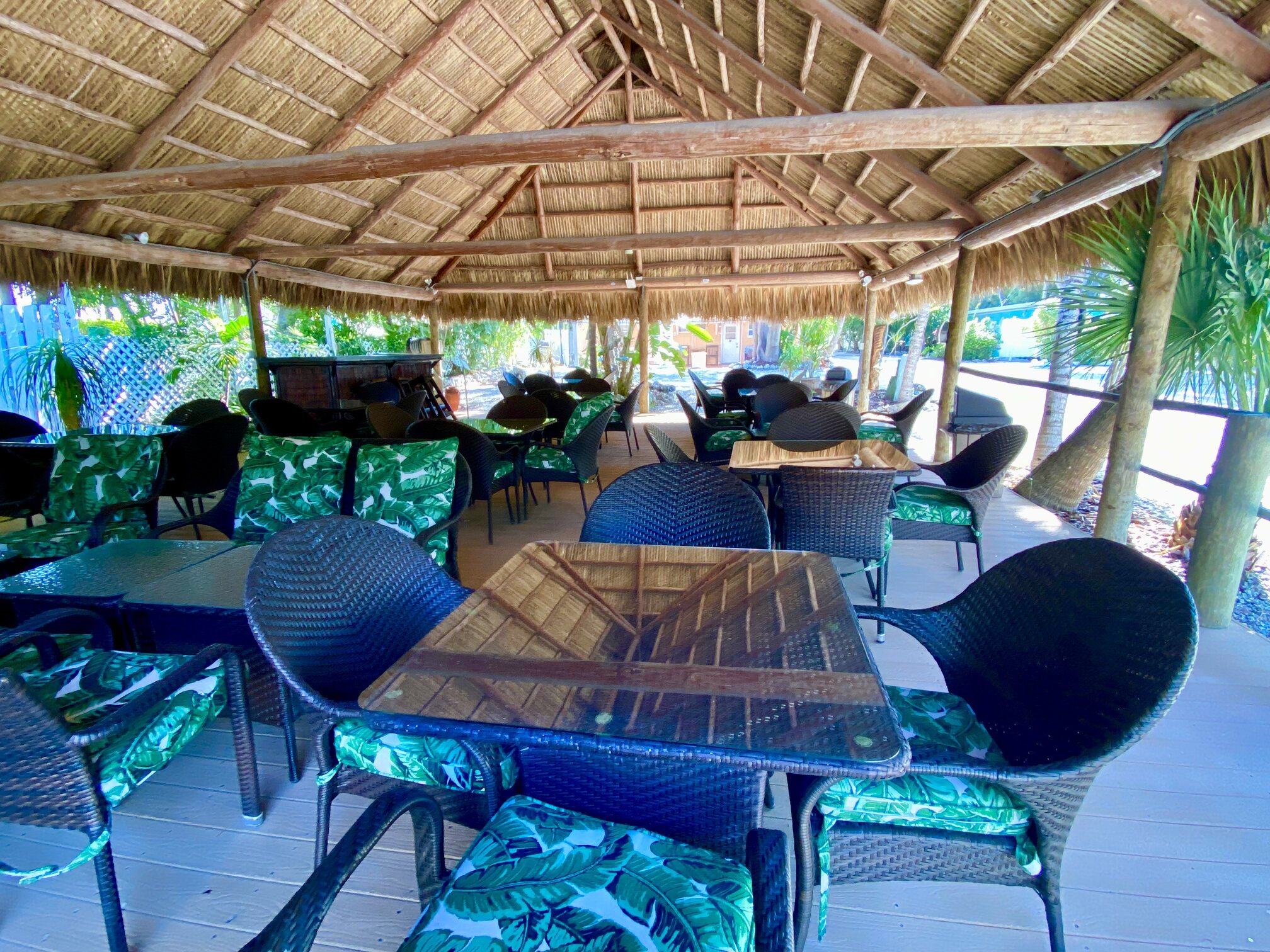Tables and chairs beneath the large thatched pavilion.