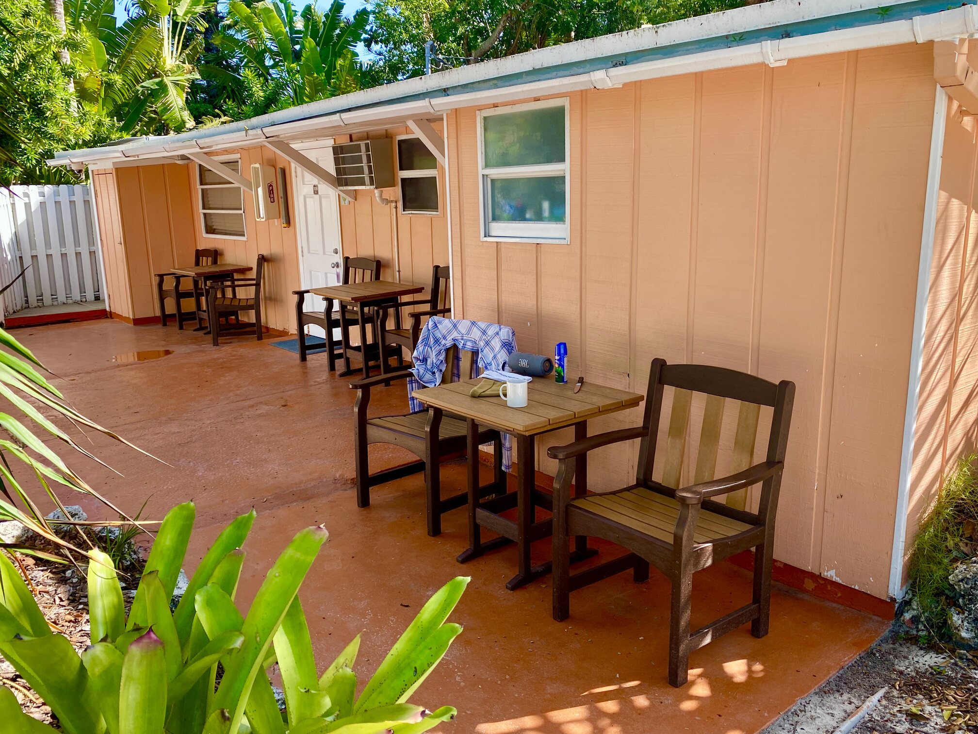 A pastel cottage porch surrounded by tropical plants.