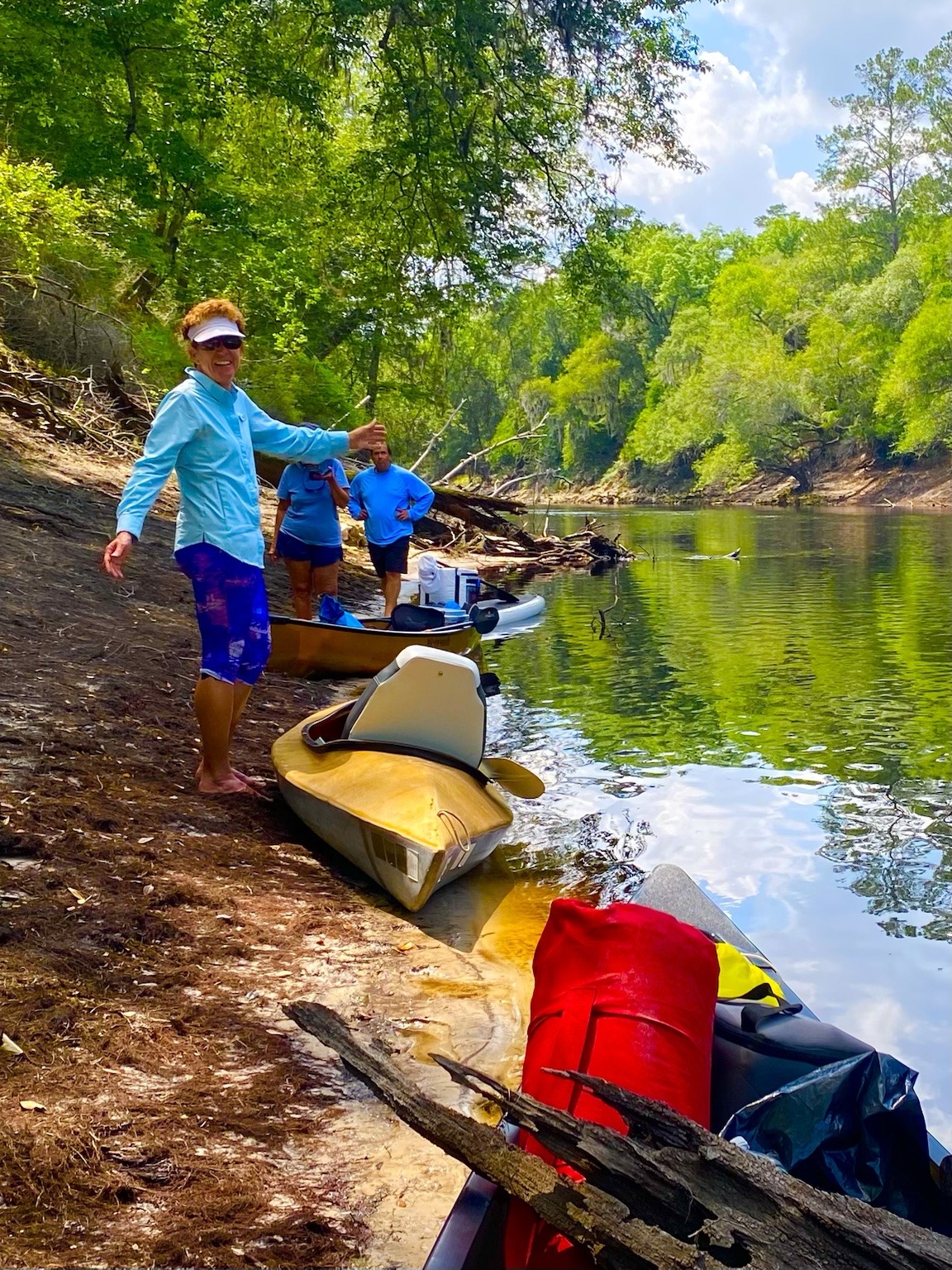 A paddler standing on the bank beside the boats during a rest stop.